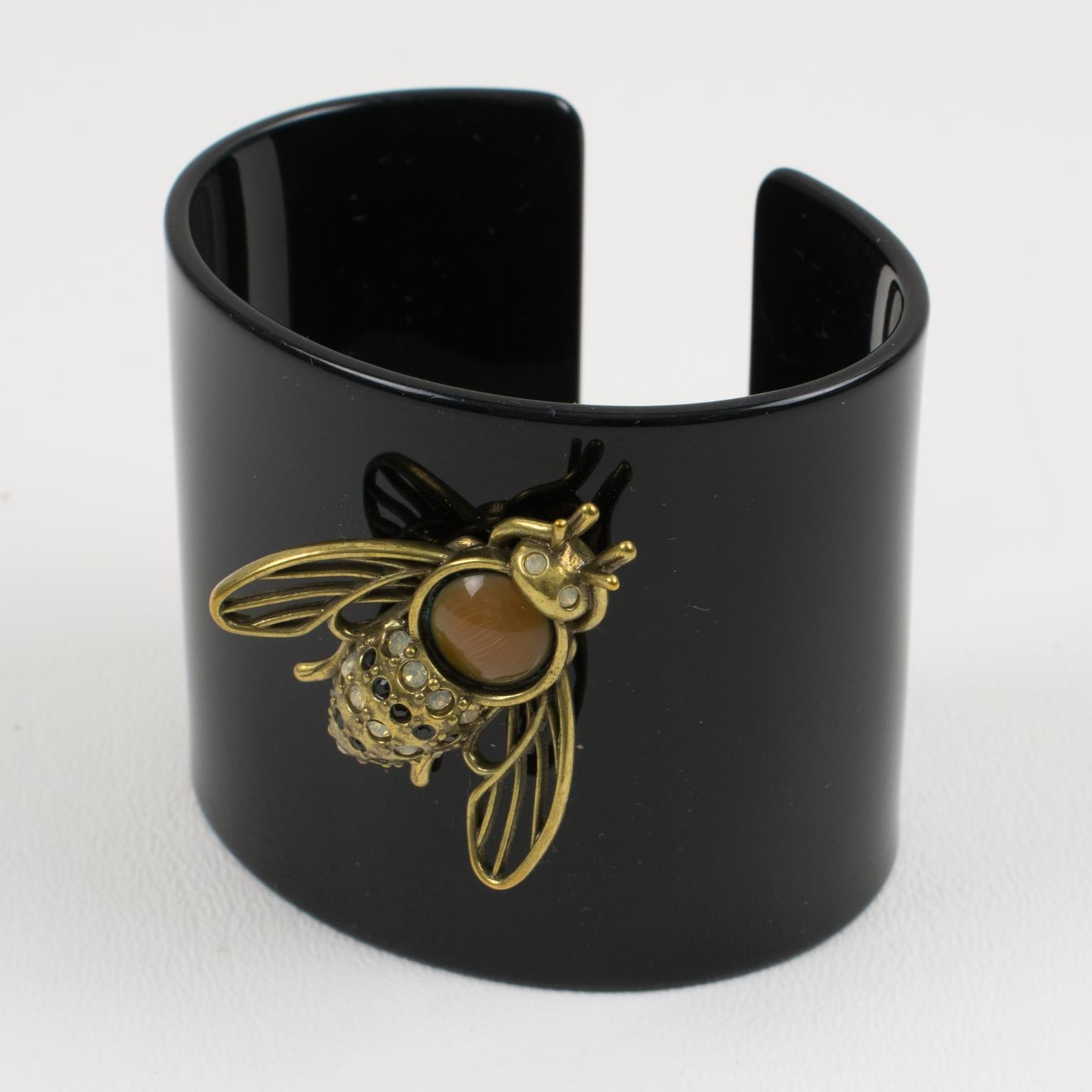 This is a lovely Jean Paul Gaultier Paris oversized black resin cuff bracelet with gilded brass bee embellishment. The bee is ornate with black and white-opalescent crystal rhinestones and topped with a large British tan poured glass cabochon. The