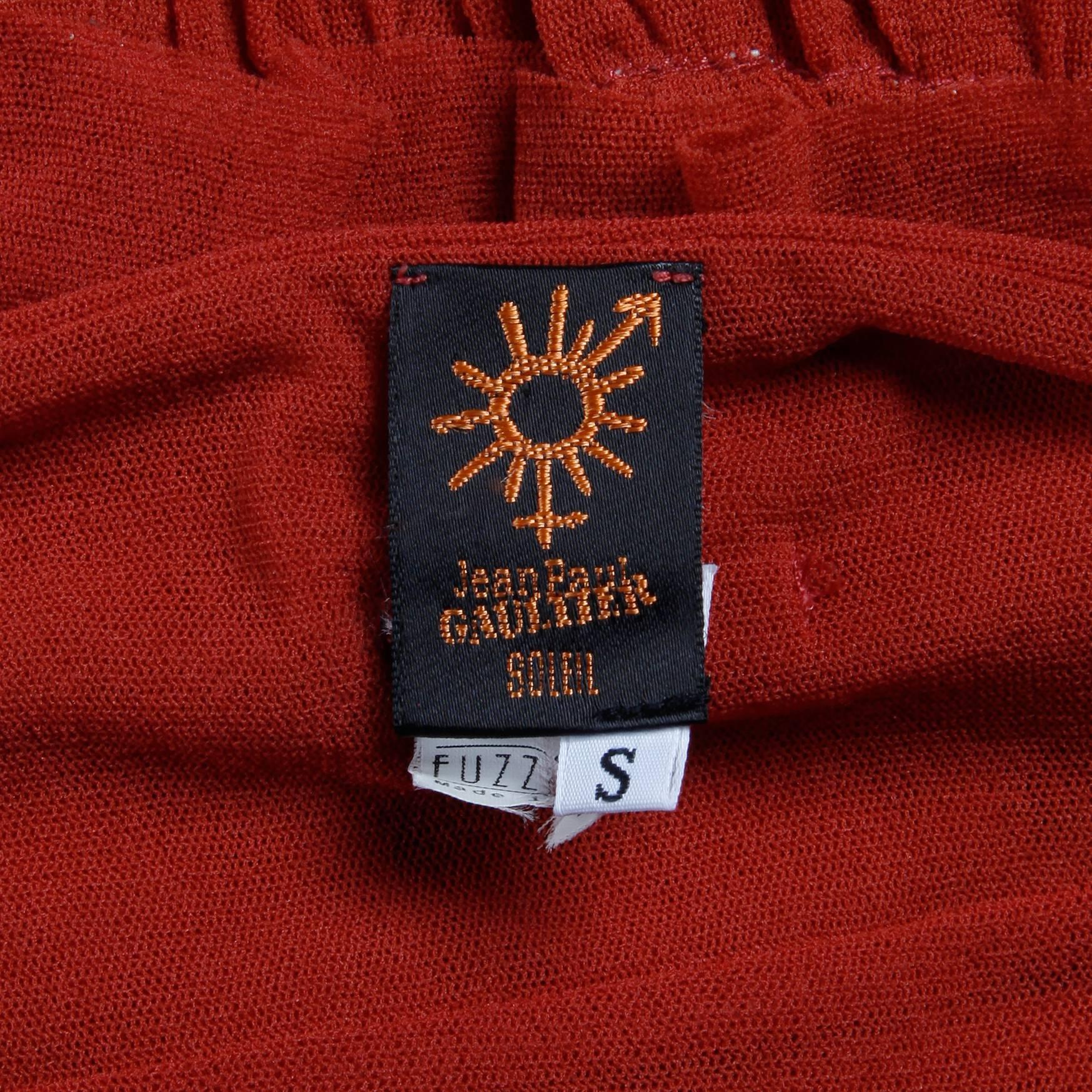 Robe rouge brique Jean Paul Gaultier avec ourlet à volants. Entièrement doublé, sans fermeture (s'enfile par-dessus la tête). 100% nylon. La taille marquée est petite. Le buste mesure 24-36
