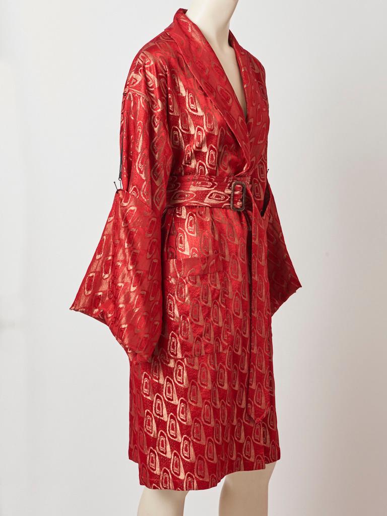 Jean Paul Gaultier, red and gold brocade belted kimono style coat/robe having a shawl collar, deep patch pockets, and extra long sleeves that can be anchored to the shoulder with a metal like detail. Belt buckle is oversized having a bronze tone