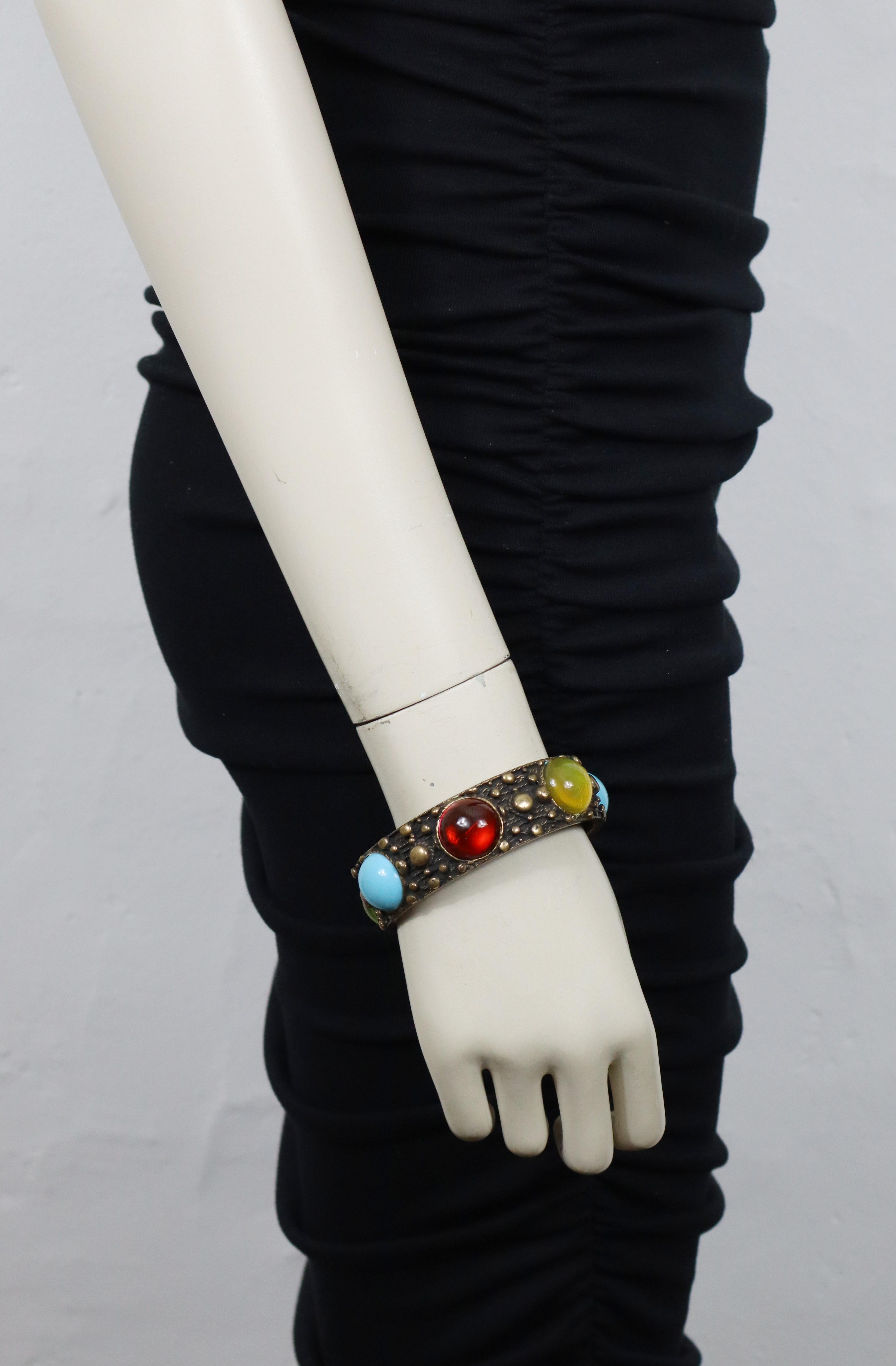 Bracciale bangle JEAN PAUL GAULTIER in bronzo anticato impreziosito da cabochon in vetro multicolore.

Con la scritta JEAN PAUL GAULTIER in rilievo.

Misure indicative: circonferenza interna circa 20,73 cm (8,16 pollici) / diametro totale circa 7,5
