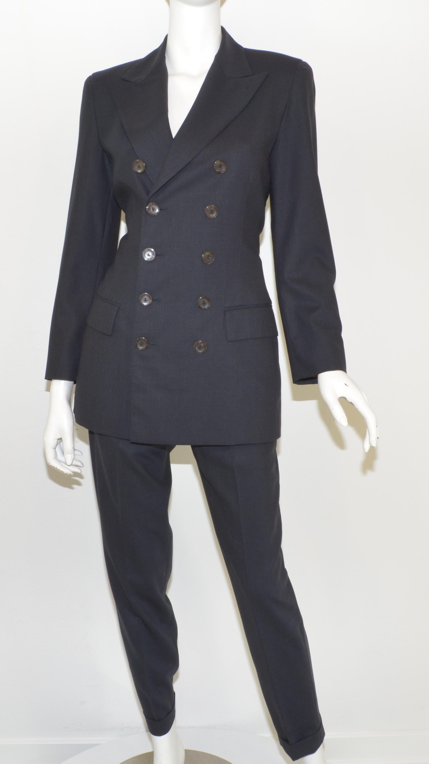 Jean Paul Gaultier pant suit featured in a dark navy color made with a wool-blend fabric. Jacket has button fastenings and pockets at the hips, full lining in a red and cream striped-pattern satin. Pants have a button and zipper fastening at the