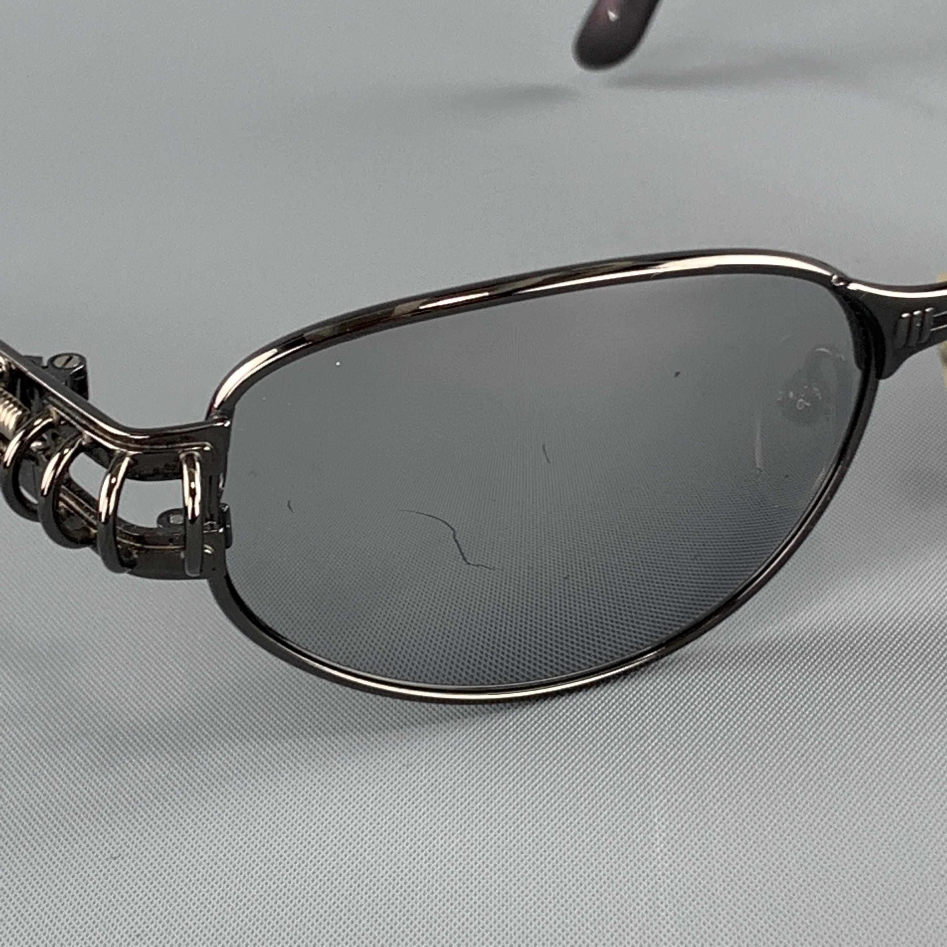 Vintage JEAN PAUL GAULTIR sunglasses come in polished smoke silver tone metal with mirrored lenses and hoop piercing detailed arms. Minor scratches on lenses. With case. Made in Japan

Very Good Pre-Owned Condition.
Marked: