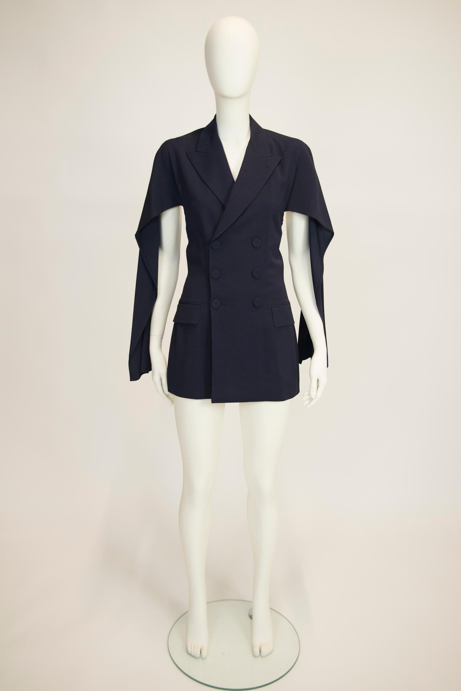 Jean Paul Gaultier's creations always have this unexpected twist that make them both recognizable and unique.
Made of navy wool (49%) and rayon (51%), this double-breasted blazer features a daring open back and slits along the sleeves that create an