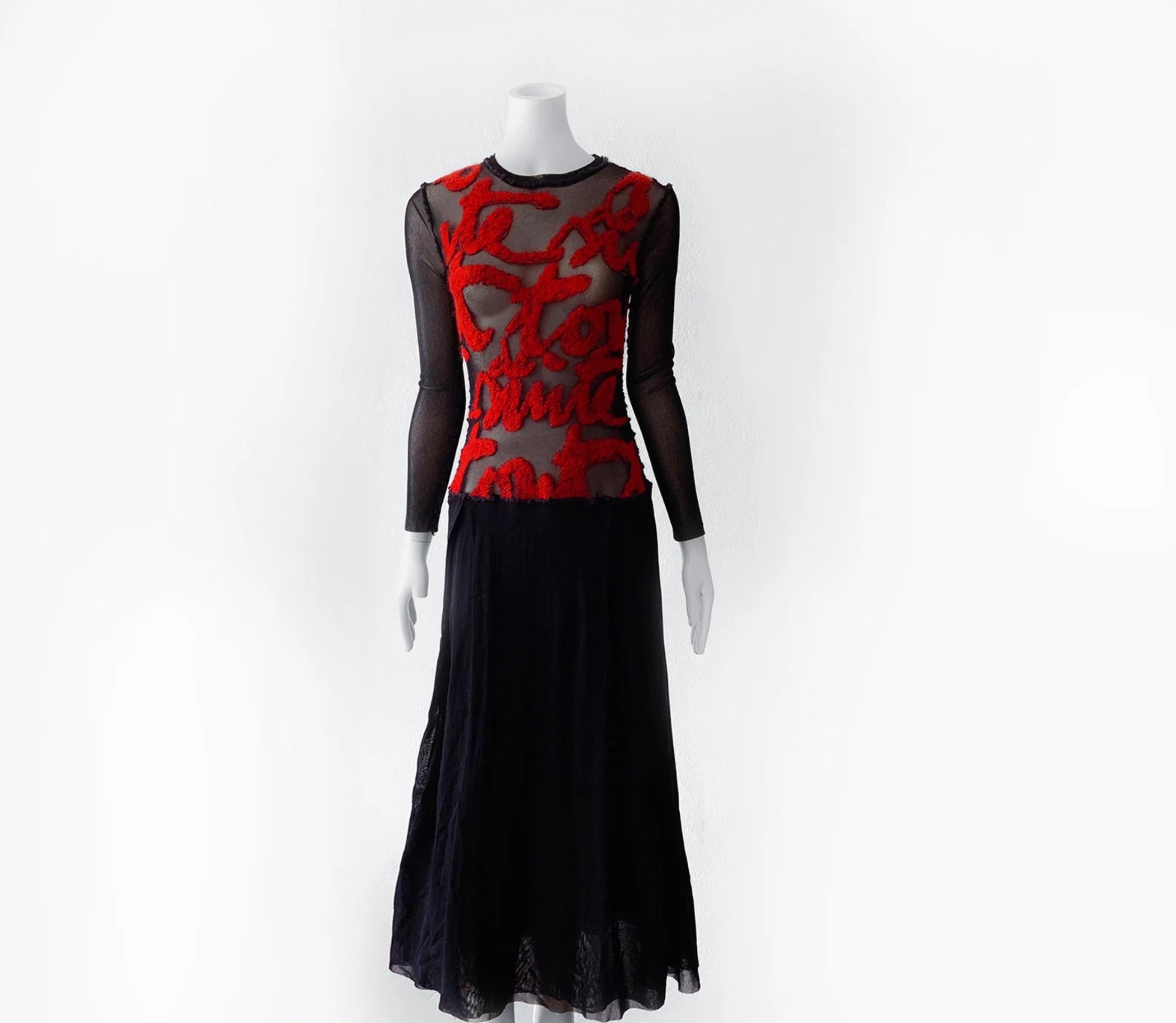 
Superbe robe iconique de Jean Paul Gaultier. Robe noire en maille semi-transparente avec manches longues et jupe à double épaisseur.
Écriture française en rouge foncé sur le devant. Il s'agit d'une icône typique de Gaultier de la fin des années 90,