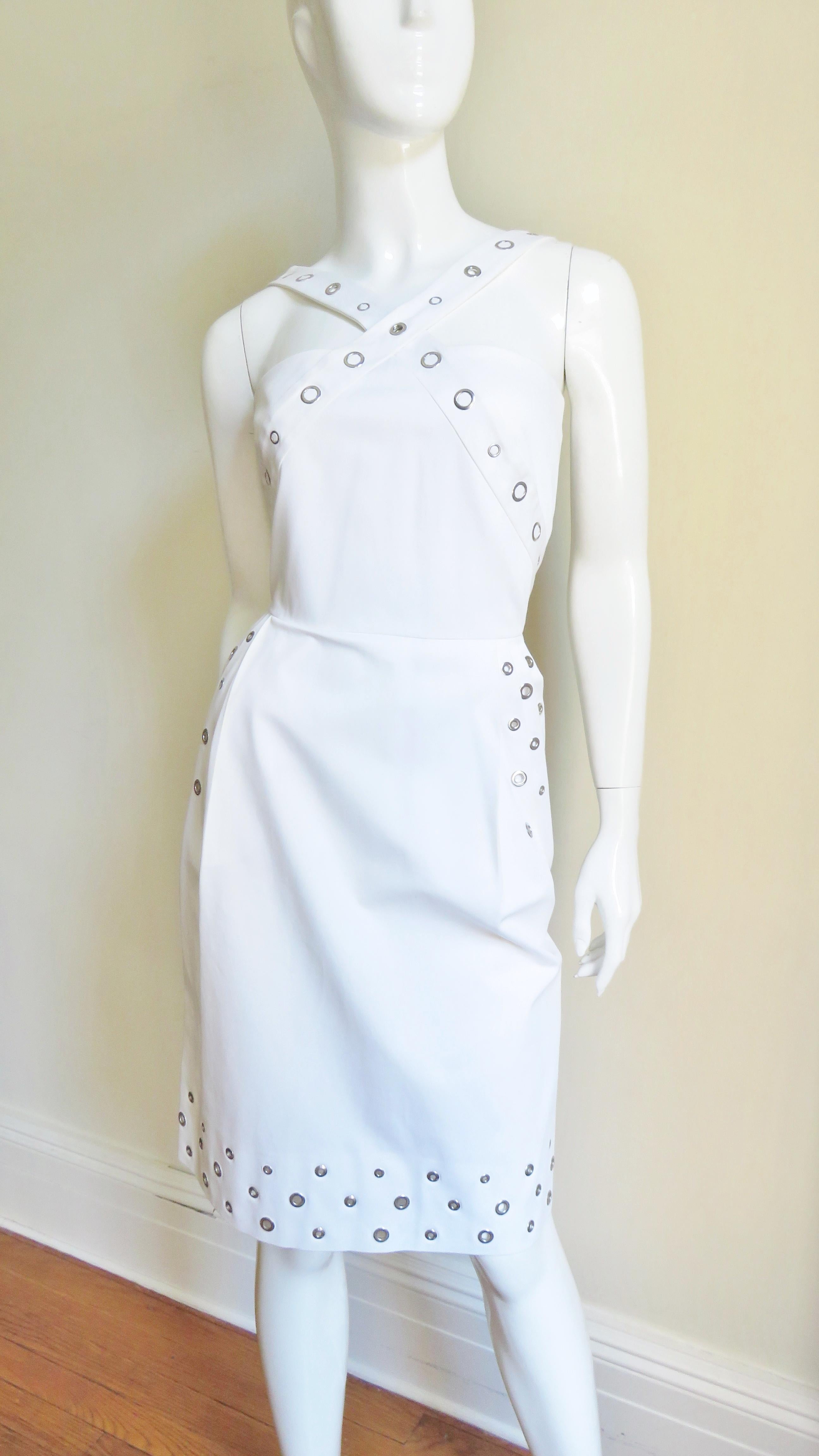 Une superbe robe blanche en coton avec un peu de stretch de Jean Paul Gaultier. Le corsage a des bretelles qui se croisent devant et derrière et la jupe droite a des poches sur les hanches. Il y a des œillets de différentes tailles le long des