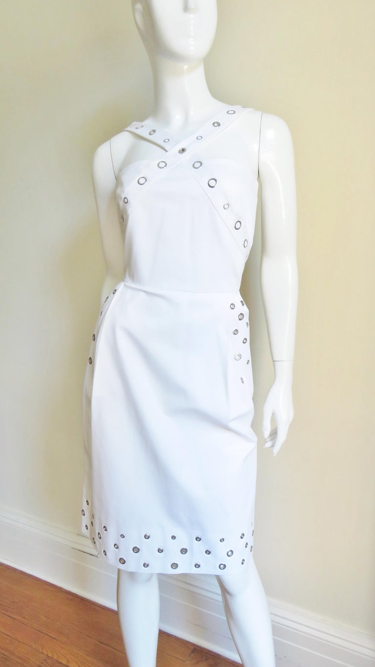 A great white cotton dress with some stretch from Jean Paul Gaultier. The bodice has straps crossing front and back and the straight skirt has hip pockets. There are grommets of varying sizes along the straps and in rows on the skirt sides and hem.