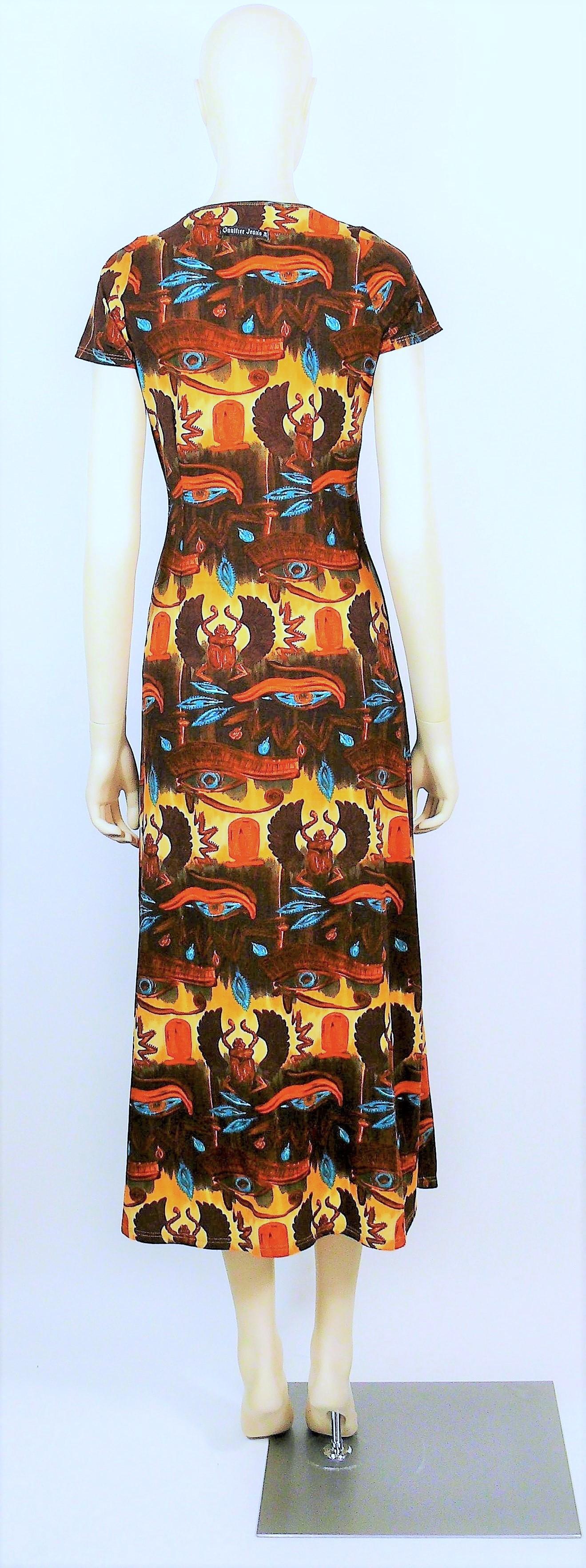 Robe vintage d'EAN PAUL GAULTIER ornée de symboles égyptiens : yeux, scarabées, cartouches et hiéroglyphes.

Cette robe présente les caractéristiques suivantes :
- Matière extensible.
- Col rond.
- Cap sleees.
- Fentes sur les deux côtés.

Un motif