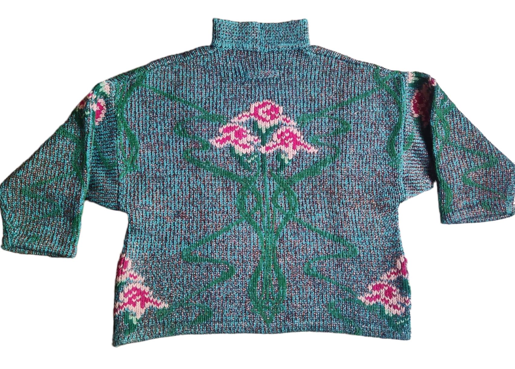 Pull en lurex de Jean Paul Gaultier de la collection automne-hiver 1984 !
Ce pull est composé de fleurs roses tricotées en fil chenille et de lurex cuivré qui lui donne un éclat subtil, conférant une touche glam des années 80 aux visuels