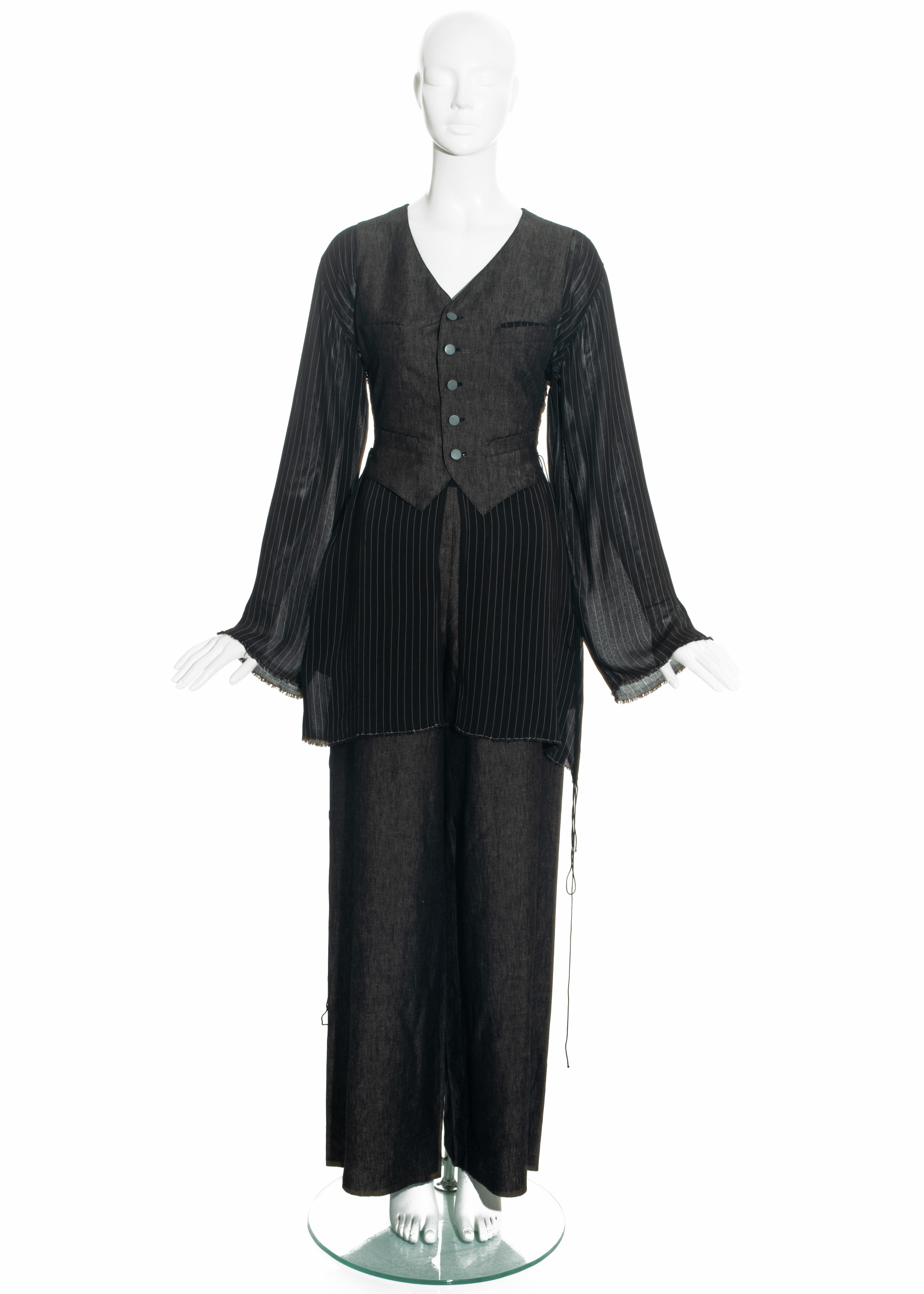 Jean Paul Gaultier pant suit comprising: grey linen waist coat with attached loose striped blouse, long lace-up fastenings on side seams, and silver metal buttons: matching grey linen wide leg pants. 

Spring-Summer 1994
