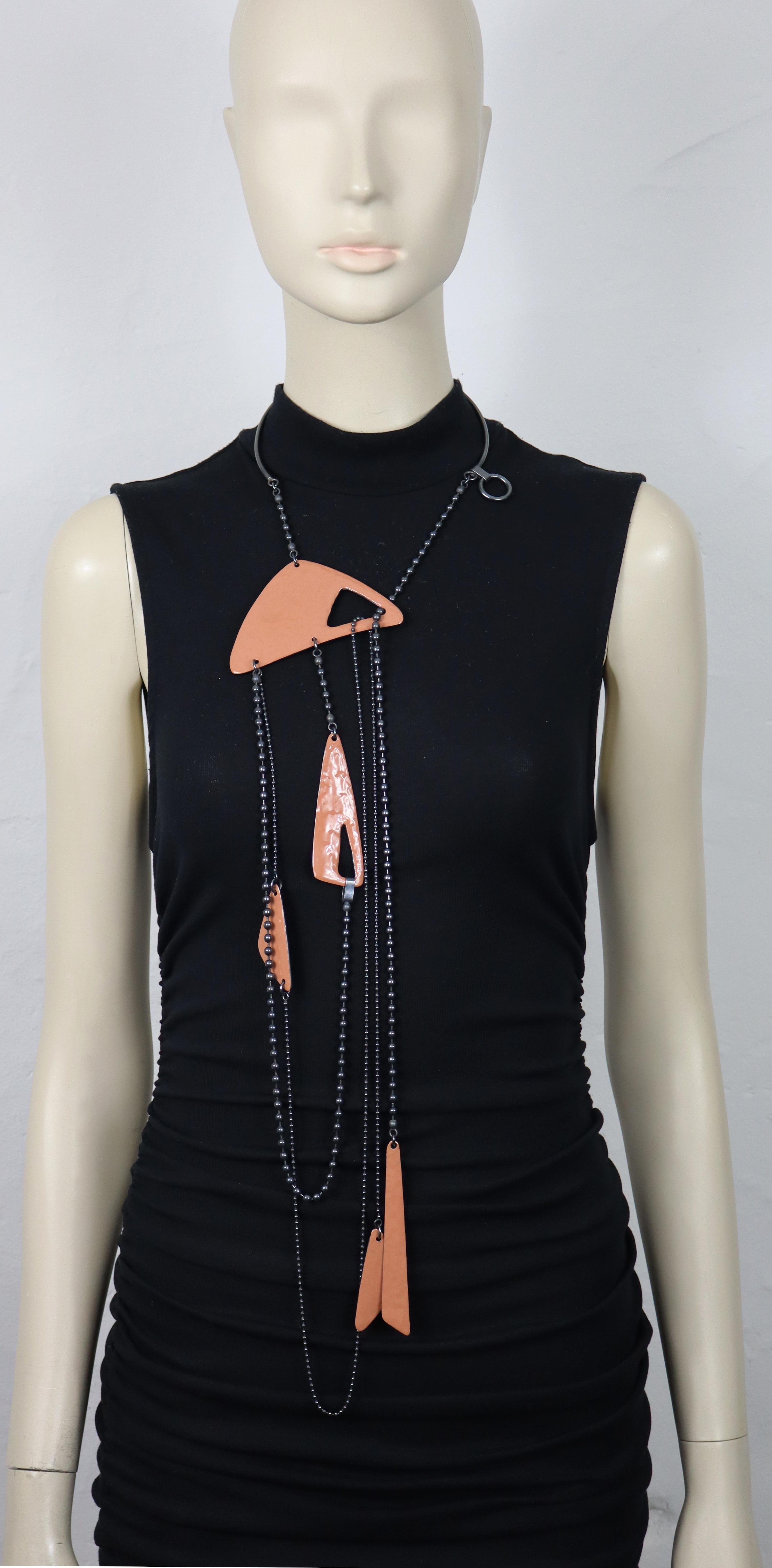 Collana mobile sautoir appesa di Jean Paul Gaultier con colletto in metallo patinato, catene multiple ed elementi astratti in smalto color terracotta.

C'è un anello che pende (e si muove) sul collare di metallo. Non siamo sicuri a cosa serva? Puoi