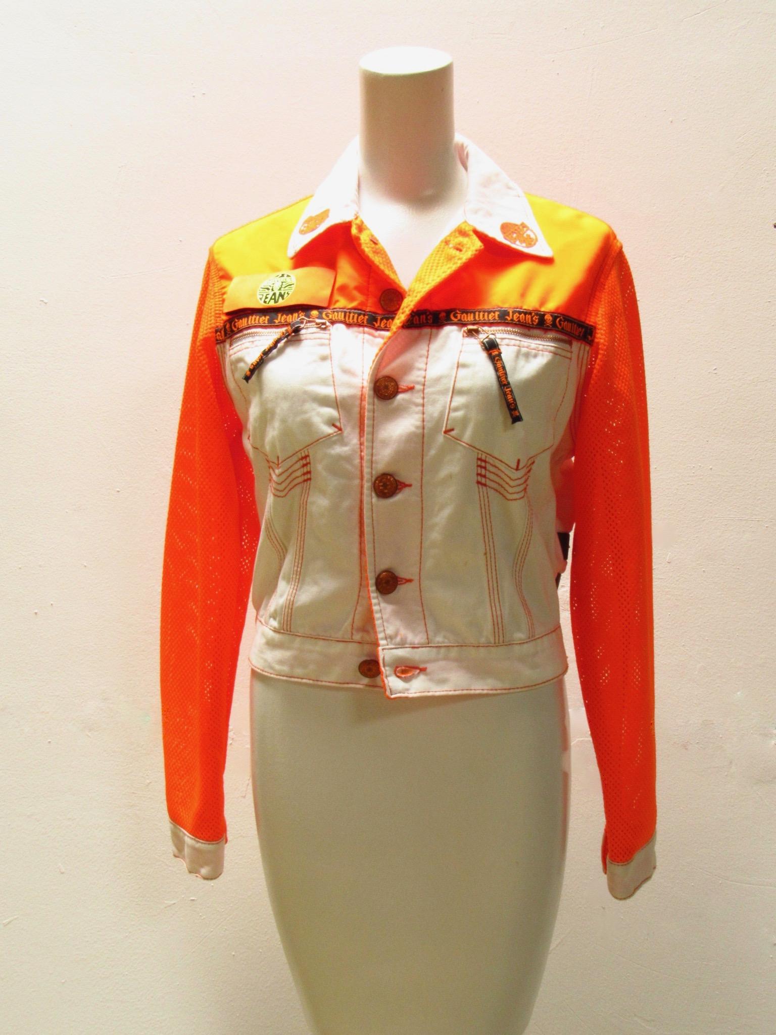 Weiße Vintage-Jean Paul Gaultier-Jacke mit orangefarbenen Ärmeln, Metallknöpfen, charakteristischen Reißverschlüssen, aufgesetzten Taschen und verstellbaren Clips auf der Rückseite. 