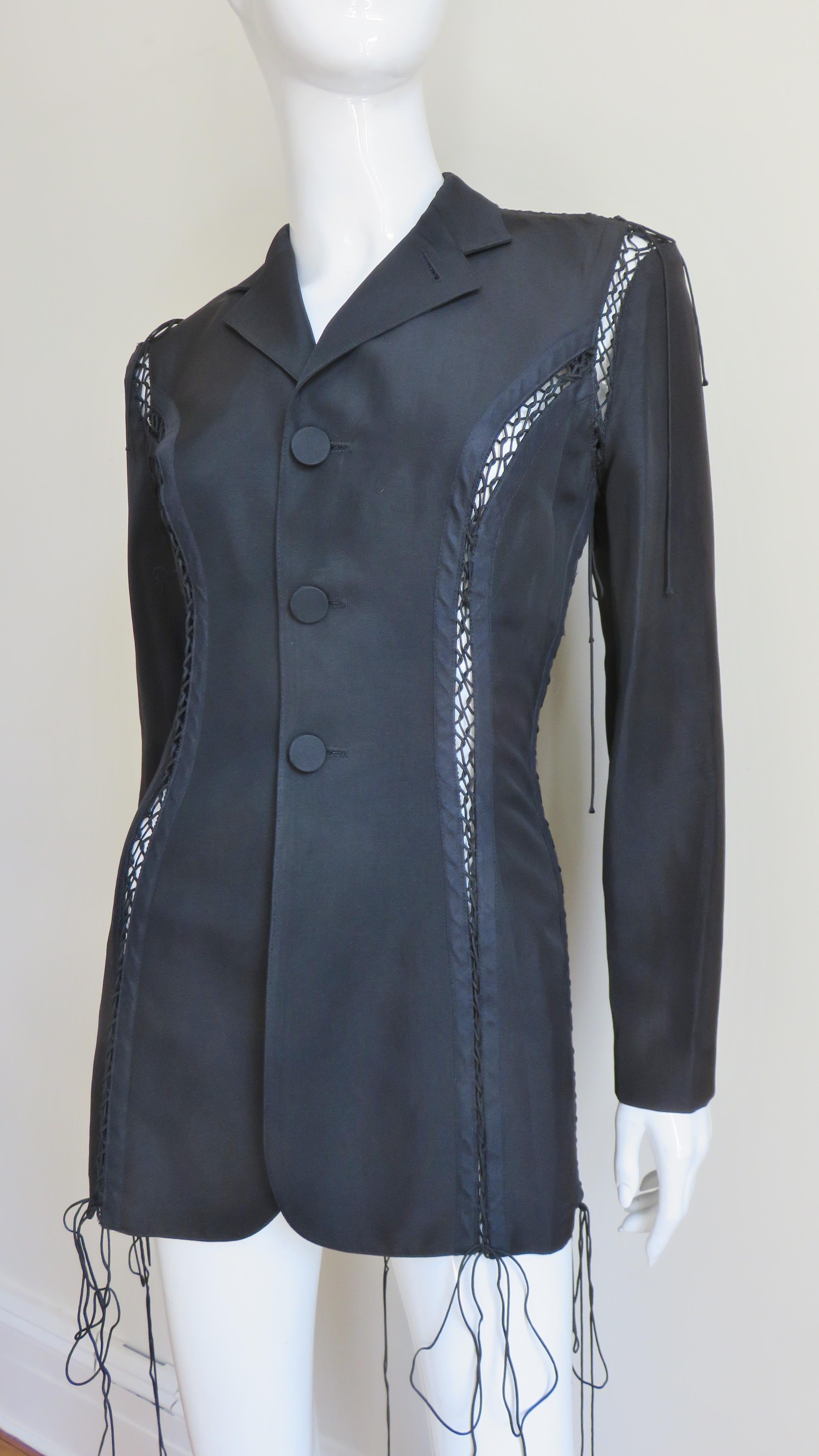 A stunning black silk jacket from Jean Paul Gaultier.  It has a lapel collar, 3 self covered button front closure plus 2 on each sleeve cuff, and intricate fine silk corded functional adjustable lacing along the jacket's seams, shoulders and