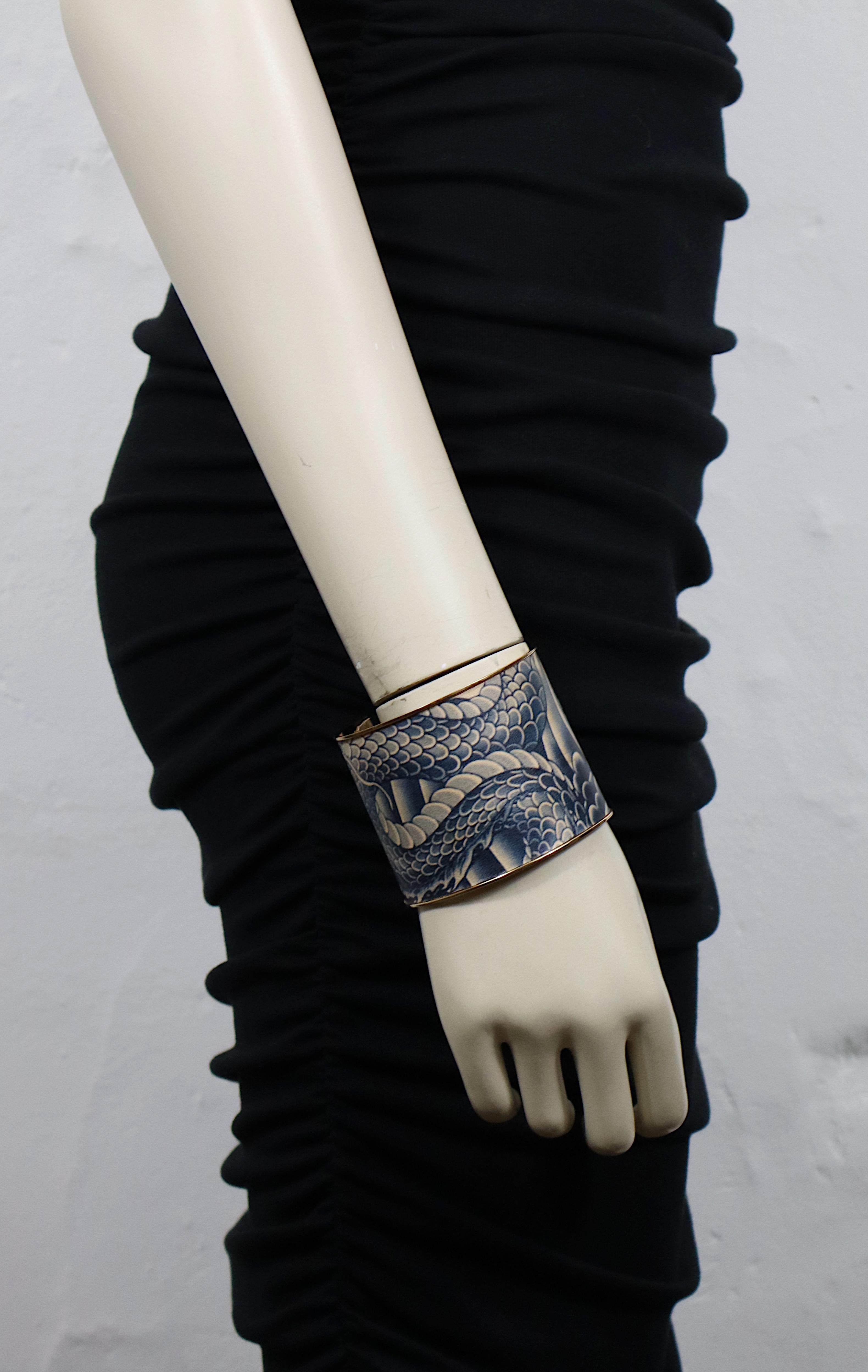 JEAN PAUL GAULTIER rose gold tone cuff bracelet covered with a blue shade and flesh colour tattoo print featuring Japanese dragon details and flowers.

Embossed JEAN PAUL GAULTIER.

Indicative measurements : inner measurements approx. 6.5 cm x 5.9