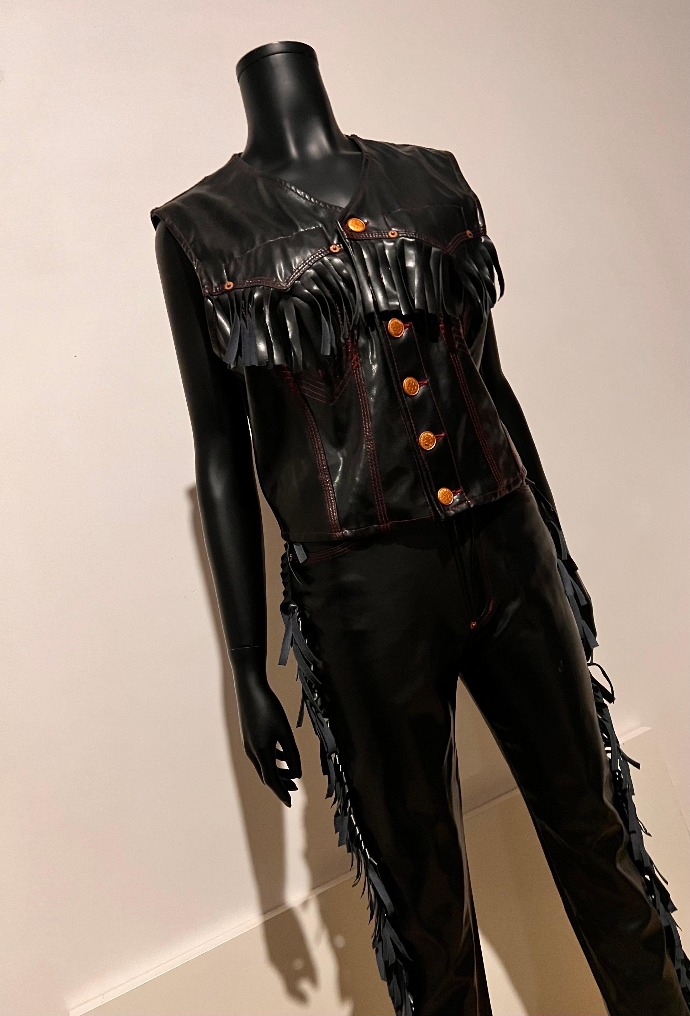 Iconic Jean Paul GAULTIER JEANS Vinyl Fringed Cowboy Western Pants and Vest.

A special piece of JPG that is truly a gender neutral garment.

Gaultier Jeans black vinyl cowboy vest and pants ensemble features fringed detail, red topstitching, and