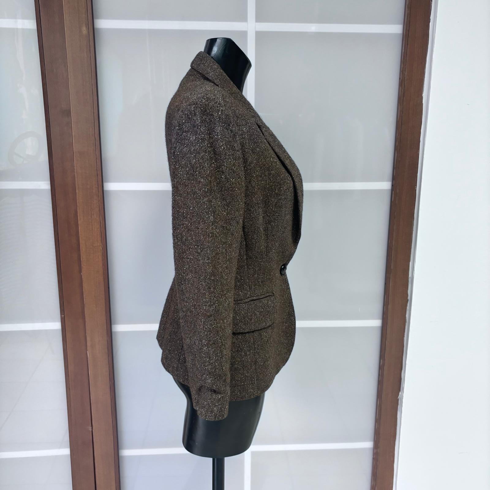 Blazer icónico Jean Paul Gaultier de la línea Junior Gaultier, confeccionado en lana marrón con cuerpo y mano compacta. La silueta está estructurada con hombros definidos, solapas clásicas y un corte ligeramente entallado que realza la figura.