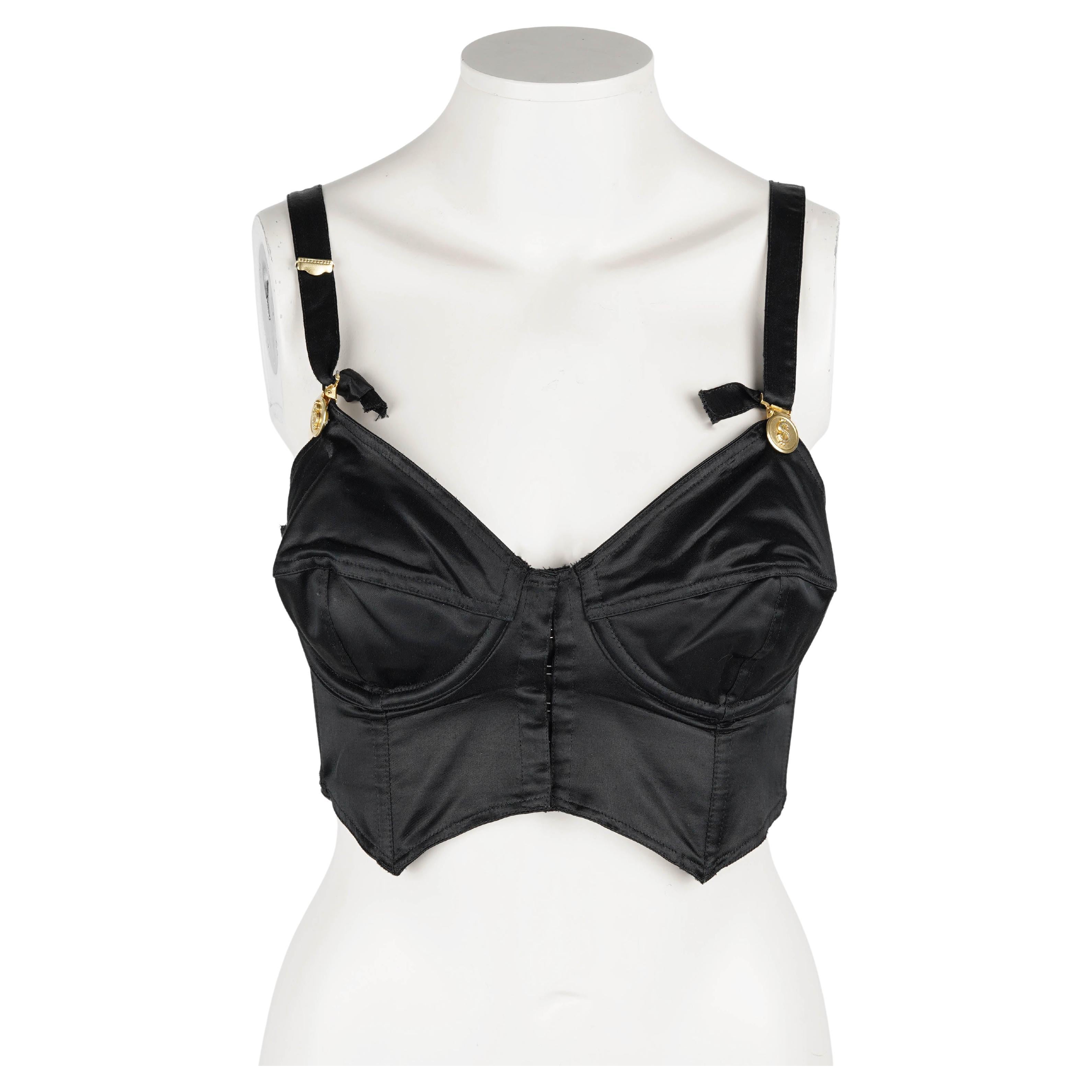 Rare early Junior Gaultier sculpted bustier from the early 1990s. Crafted in black cotton-viscose satin (70% cotton / 30% viscose) with structured cone cups, it showcases Gaultier’s signature corsetry-inspired construction and gold-tone dollar-sign