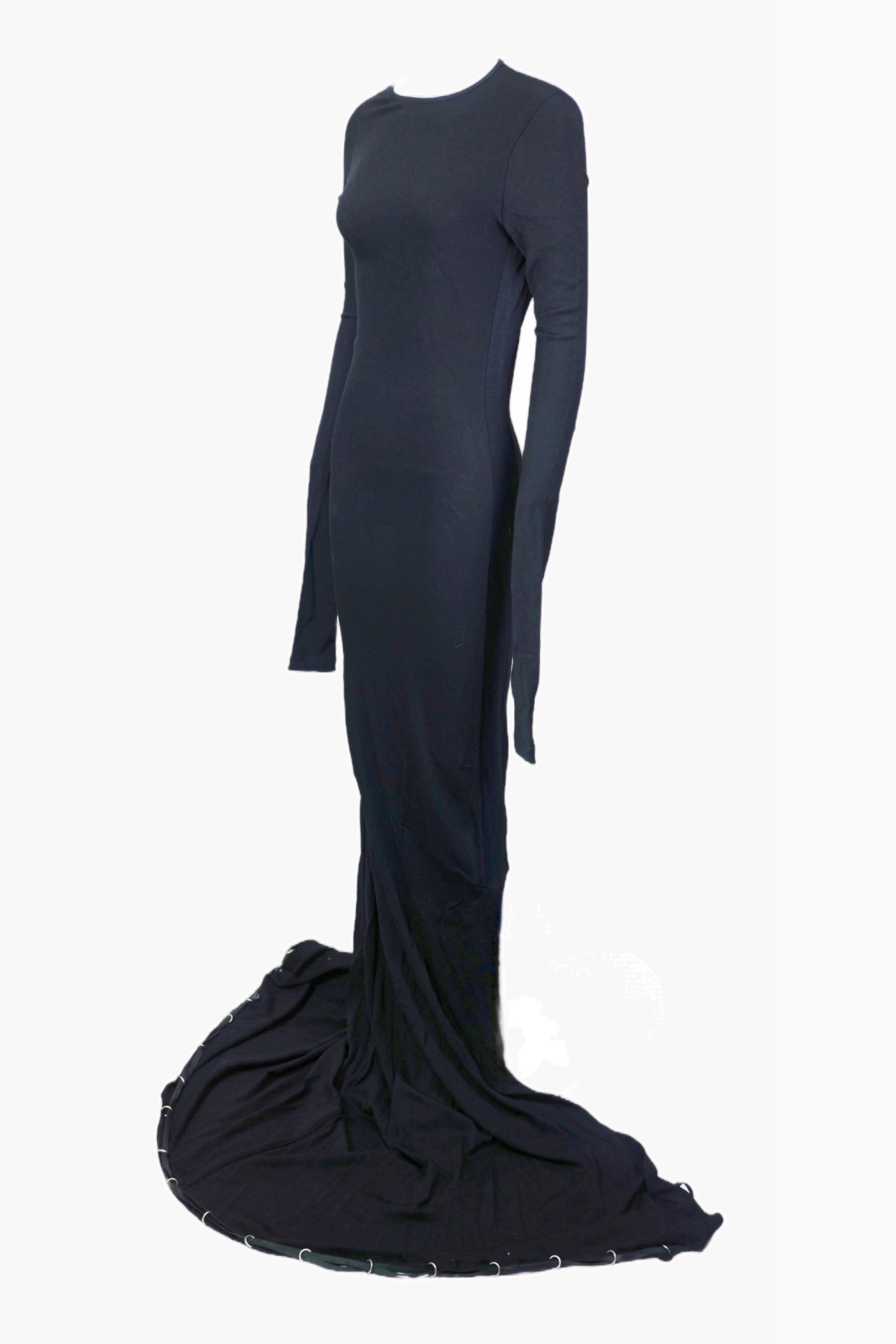 Este elegante vestido negro de la colección de finales de los 90 de JEAN PAUL GAULTIER presenta una silueta entallada con un diseño hasta el suelo que se prolonga en una espectacular cola, creando un look llamativo y atemporal. Las mangas largas y