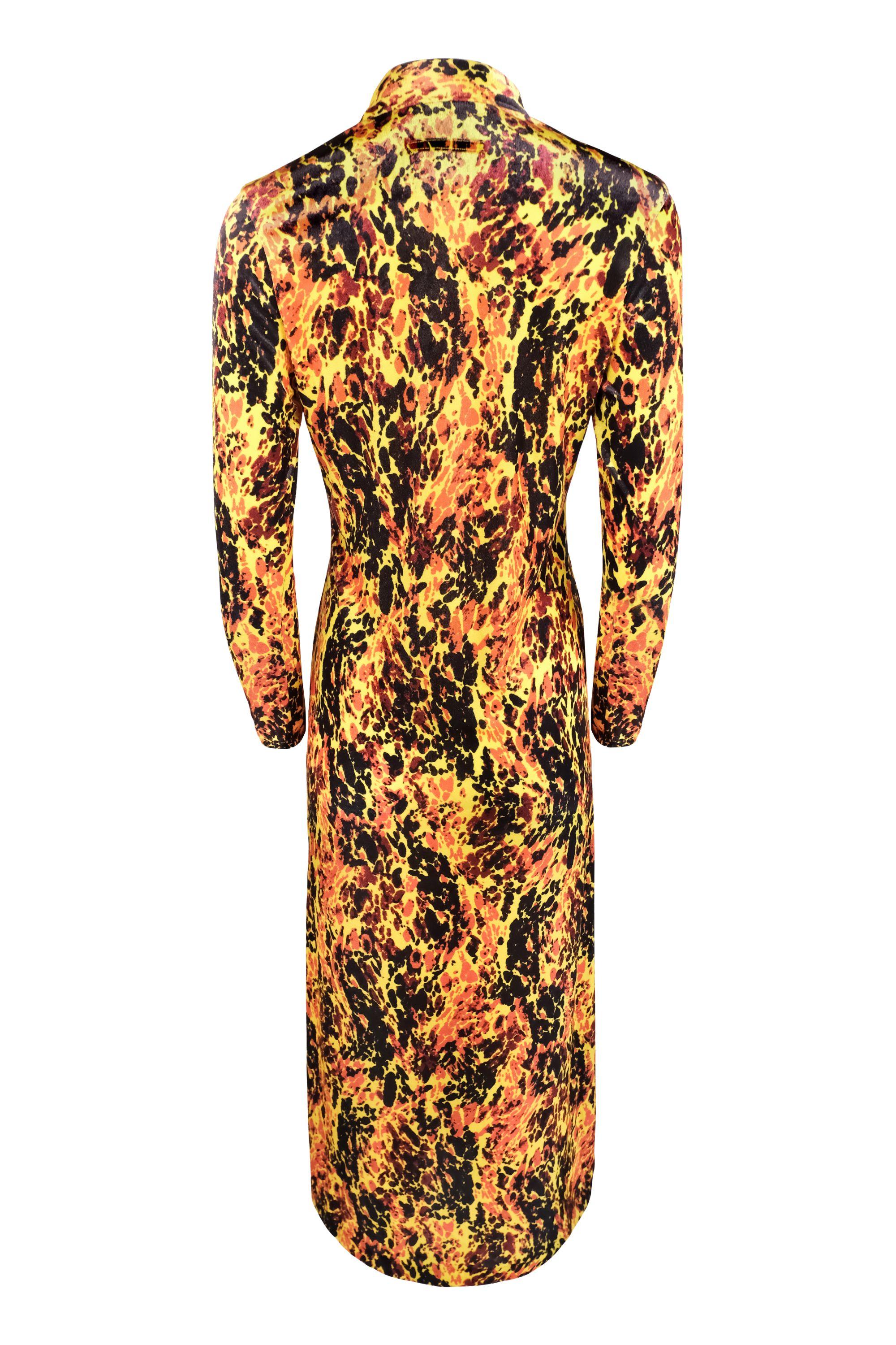 This striking Jean Paul Gaultier dress is a commercial variation of a look from the Spring 1997 collection. Made from velour, it features a vibrant lava print in yellow, orange, and black. The dress has a deep V-neckline with buttons down the front,