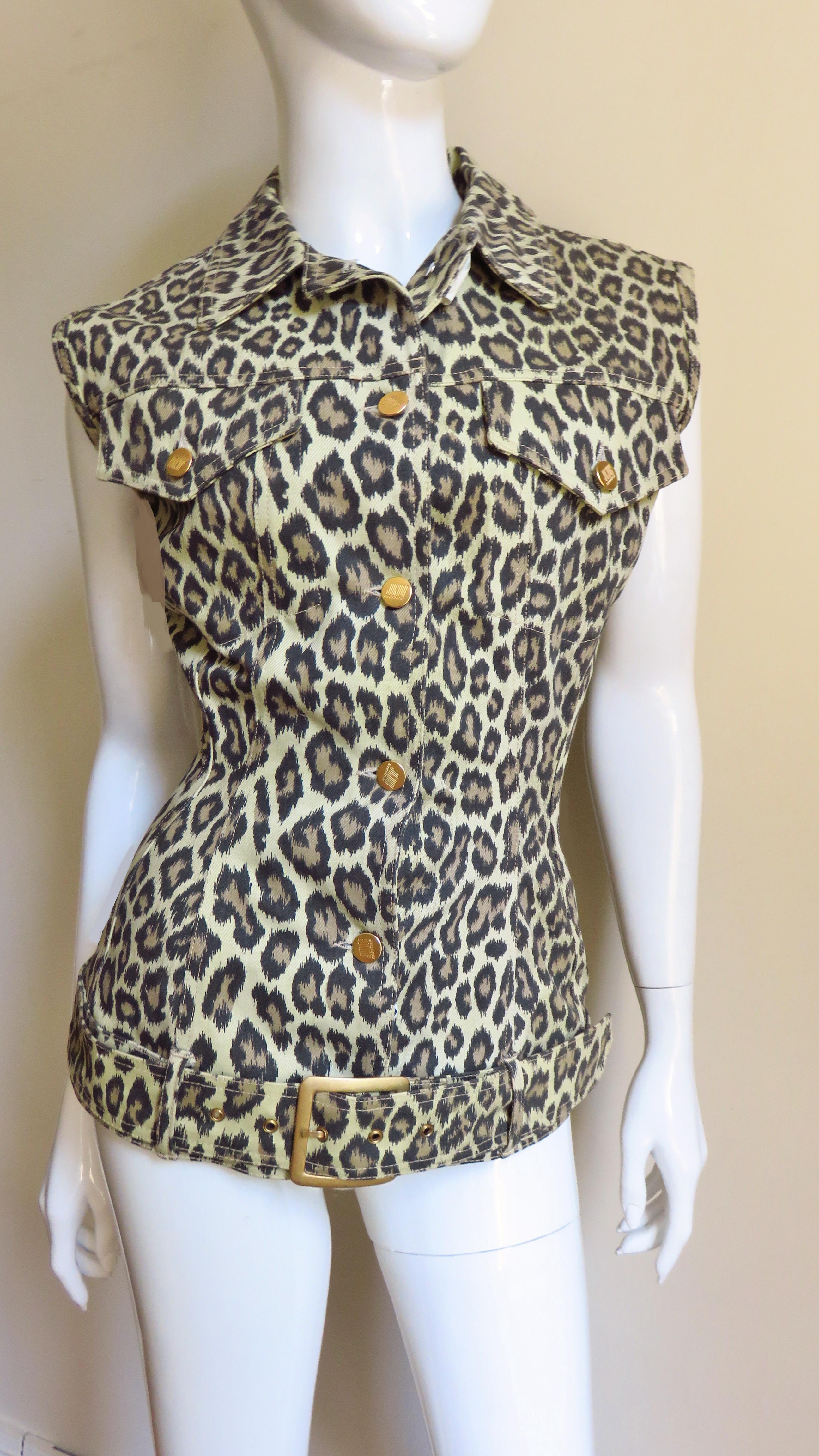 A fabulous leopard print denim sleeveless vest, jacket, top from Jean Paul Gaultier's Junior Gaultier line. It is sleeveless with a collar, button chest pockets, gold Gaultier inscribed metal buttons up the front and it has a hip belt with a metal