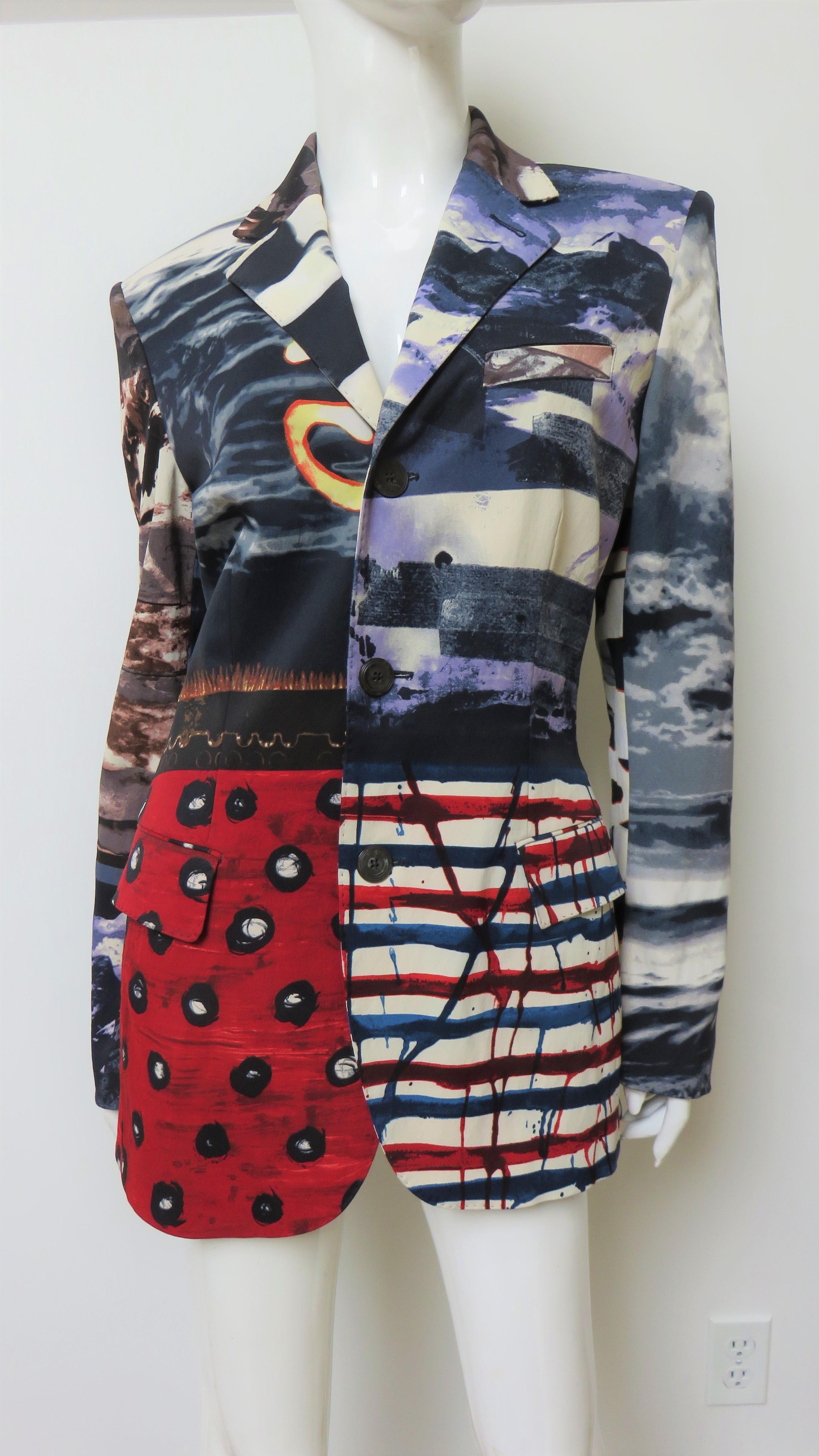 A gorgeous patchwork multi pattern jacket from Jean Paul Gaultier in a blue, red, off white and black abstract pattern and photo print.  It has a hand stitched lapel collar, 2 front flap pockets and center front and cuff button closing.  The top