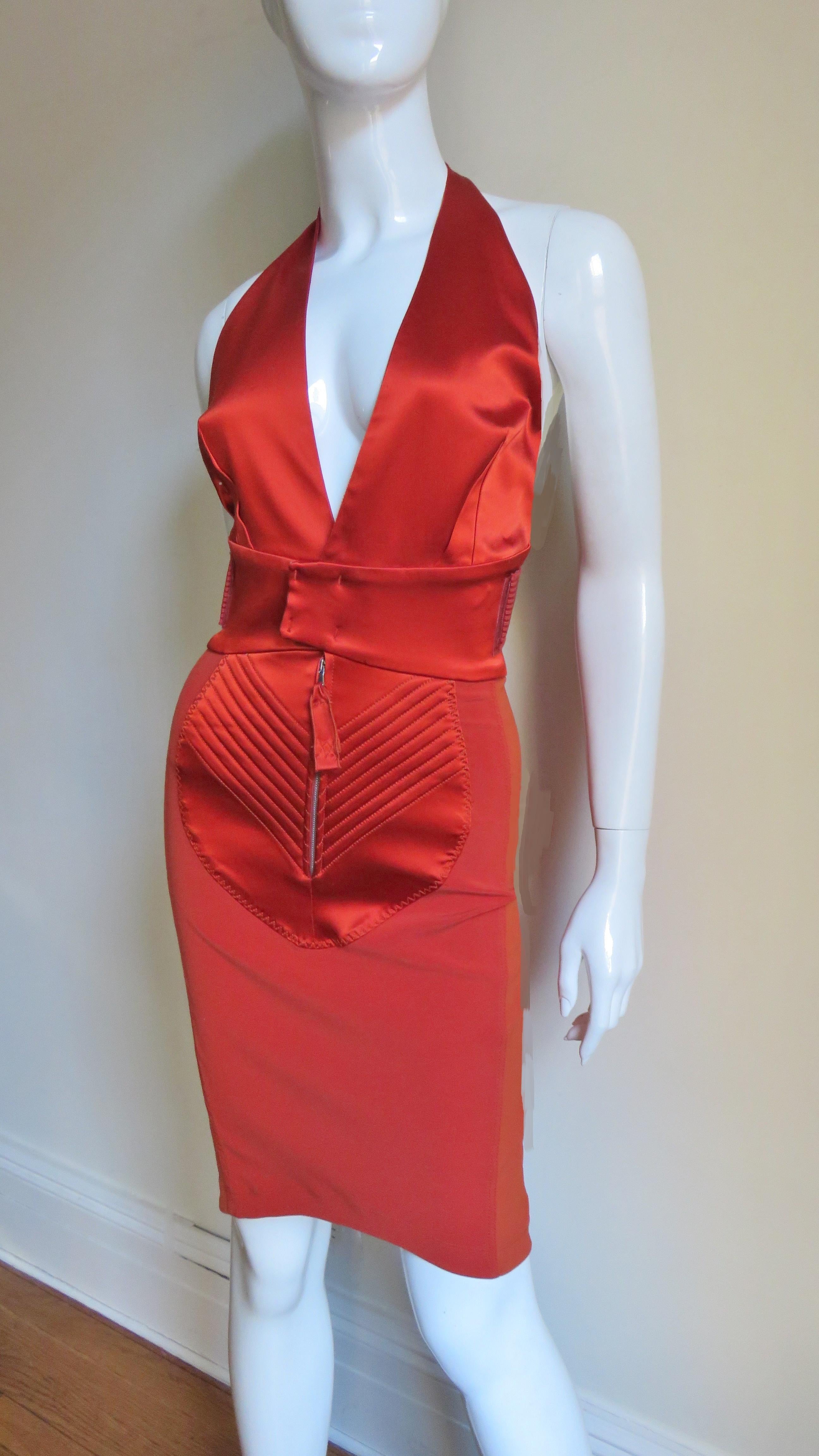 This is a fabulous tangerine stretch satin dress from Jean Paul Gaultier very rich in detail.  It has a plunging halter neckline with interwoven stretch bands at the back waist that cross through an oval matching leather vertical panel.   The skirt