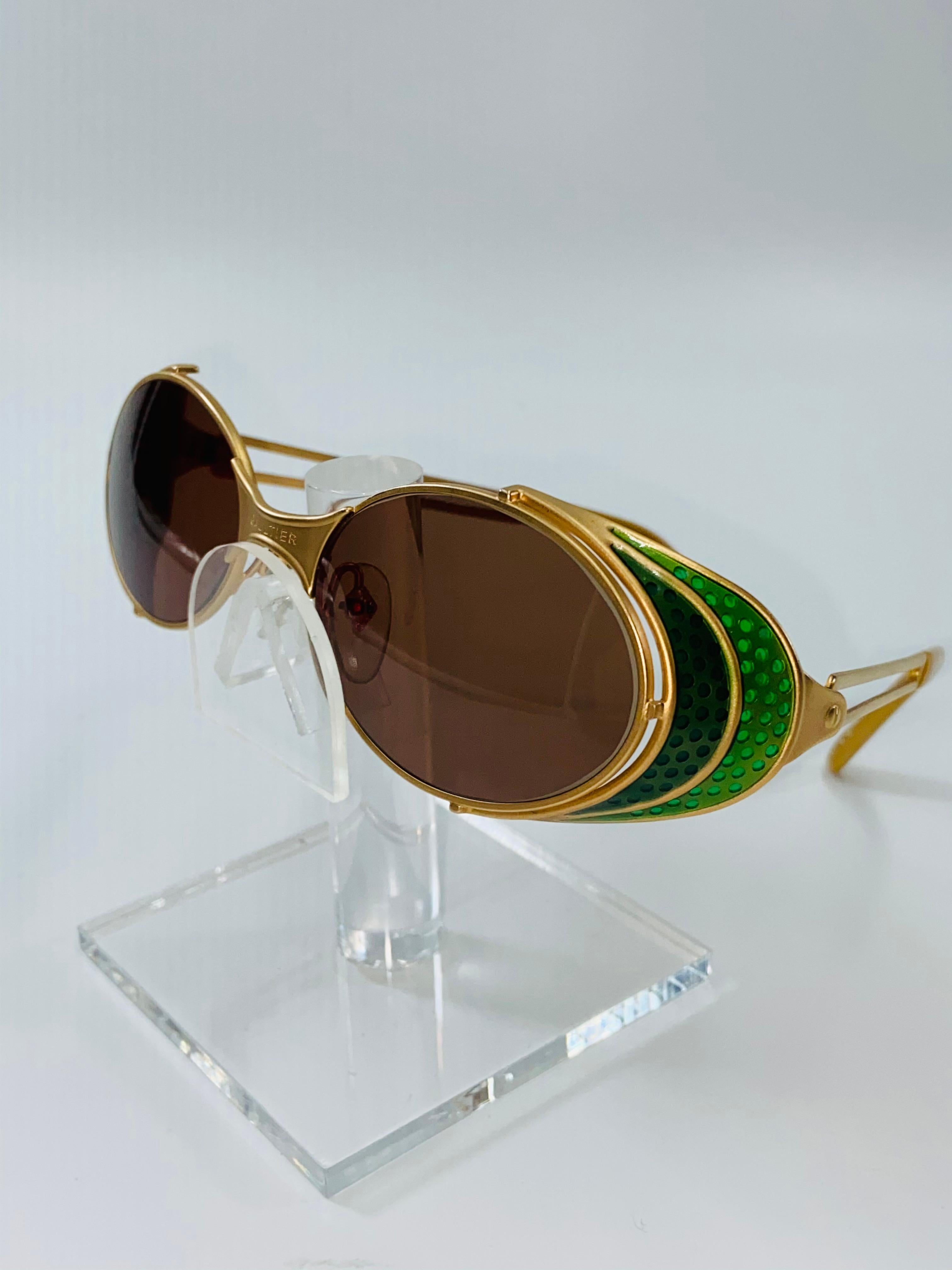 Jean Paul Gaultier Rare Vintage Green Enamel & Gold Steampunk Sunglasses
Matt Gold tone metal frame with two tone decorative green enamel detail on side of eyes
Gaultier stamped across the nose bridge 
Tinted lenses.

Max width 6 3/4 in.
Lenses