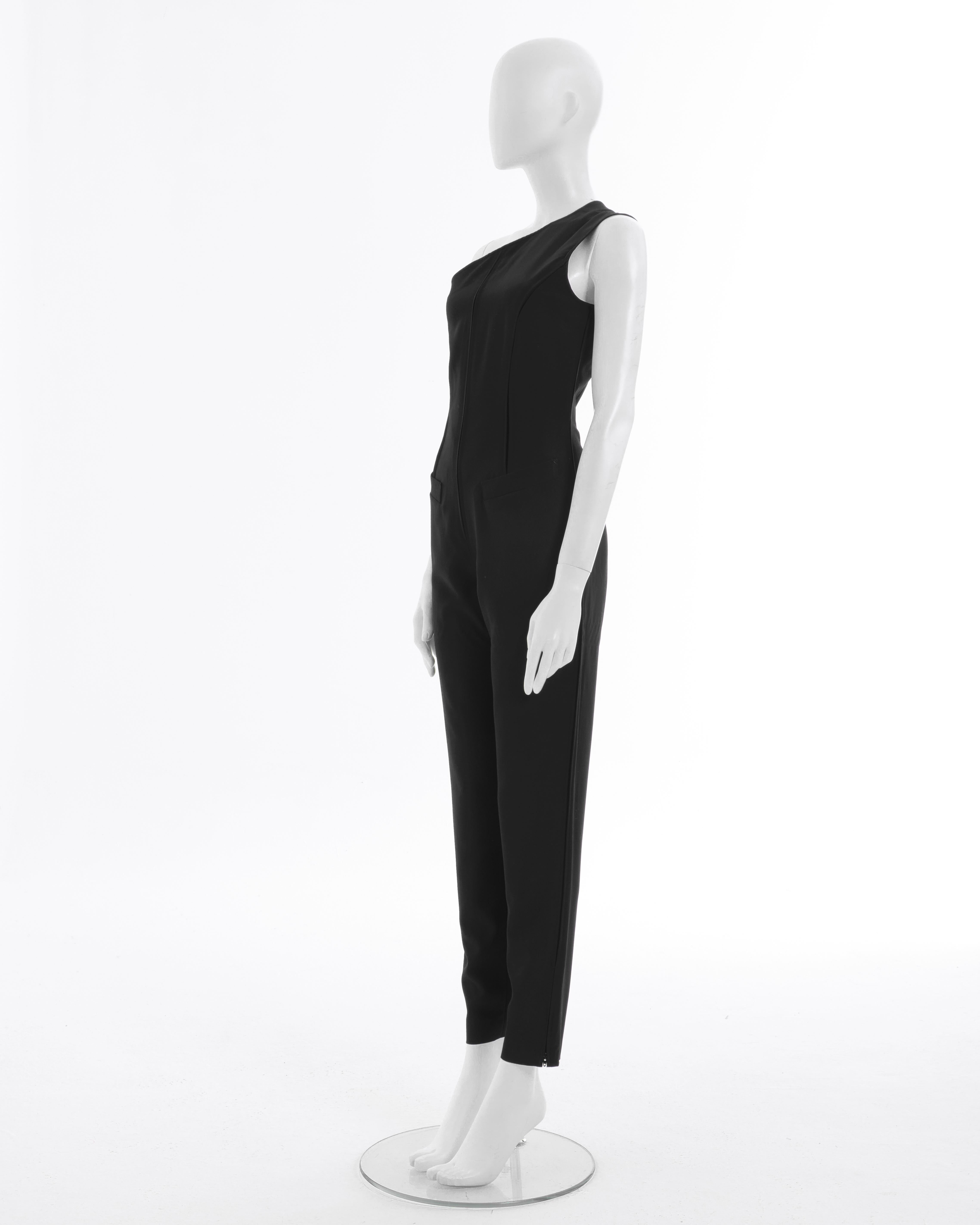 - Jean Paul Gaultier Combinaison noire à une épaule
- Vendu par Skof.Archive 
- Printemps-été 1990  Rhapsodie en bleu
- Adapté au corps 
- Fermeture à glissière sur le côté de la martingale au dos 
- Deux fermetures à glissière également au bout des