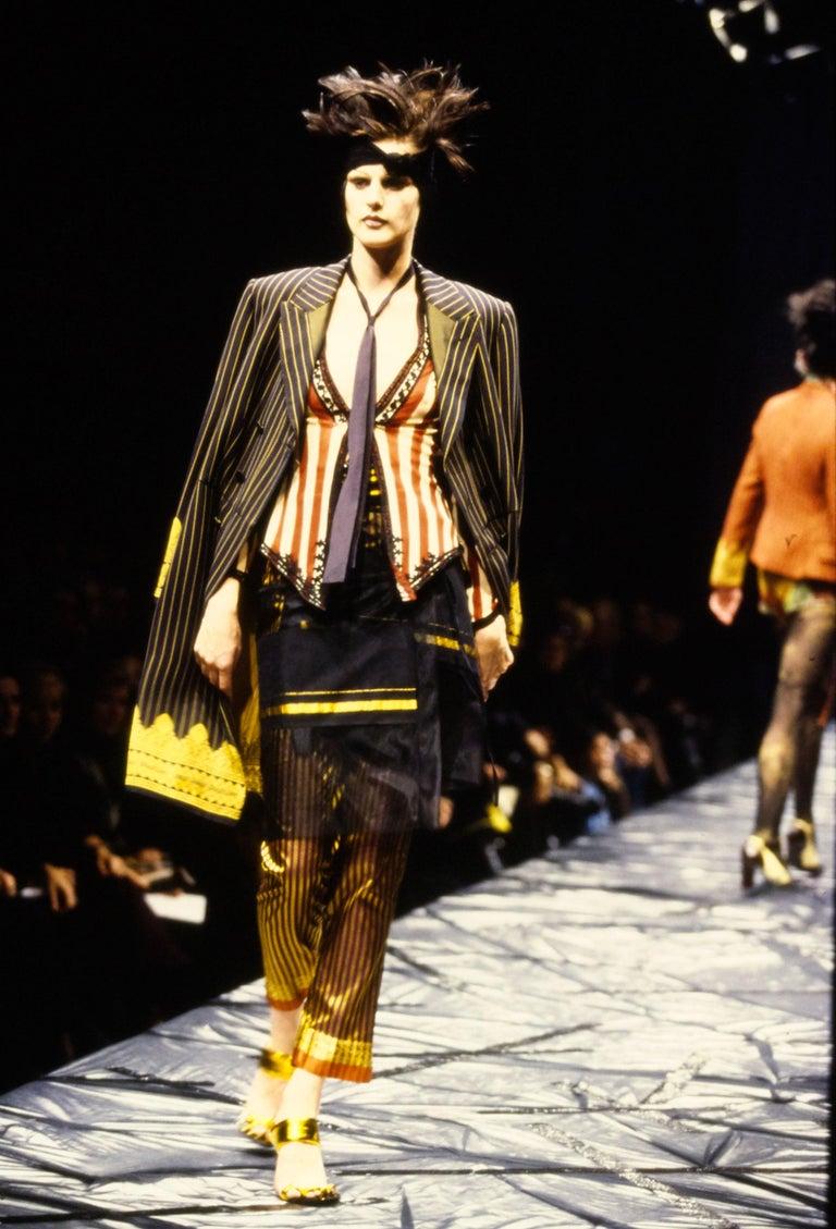 - Archival Jean Paul Gaultier black pinstripe Jacquard wrap skirt
- Sold by Skof.Archive 
- Spring - Summer 1997 
- Adjustable wrap skirt 
- Arabesque Jacquard brand name at hems
- Material: 53% rayon, 47% acetate
- Size: FR 38 - EN 42 - UK 10 - US