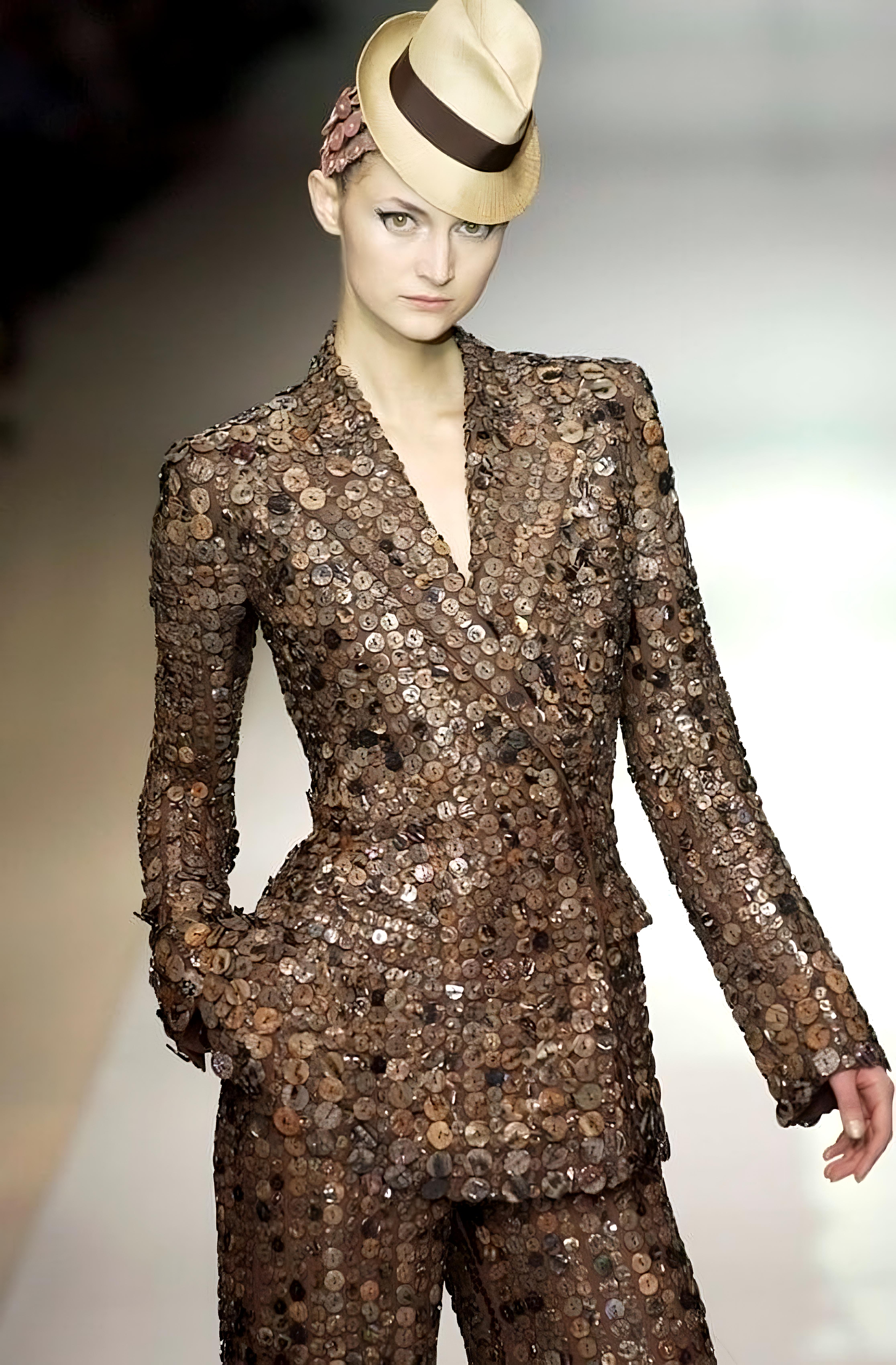 - Entworfen von Jean Paul Gaultier
- Frühjahr-Sommer-Kollektion 2003 Haute Couture
- Mehrere Hinweise auf der Startbahn
- Schwarzer Blazer aus Wolle mit Perlmuttknopfverzierung
- Besonderes Merkmal: mehrere schillernde Perlmuttknöpfe an Revers und