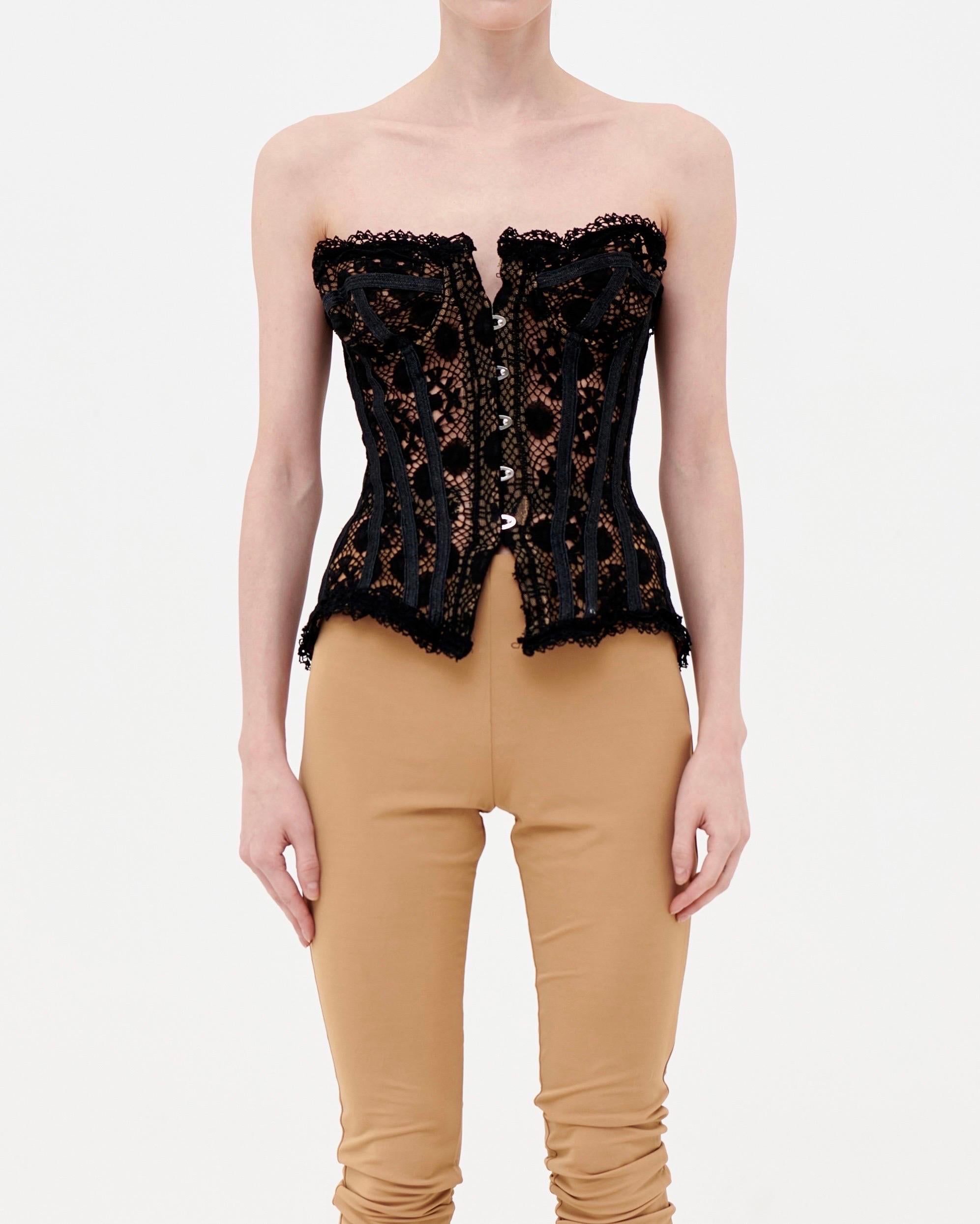 • Sheer black lace corset top
• Nude mesh lining
• Front hook closure
• Back lace-up fastening
• Runway piece