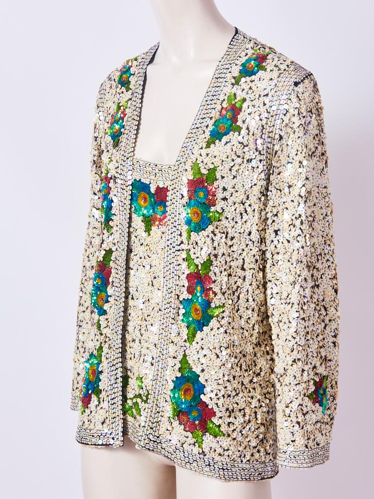 Jean Paul, Gaultier, cardigan set, having an open cardigan and matching camisole. Both pieces are encrusted with ivory tone sequins over black tulle. A  multi tone, sequined floral pattern, embellishes the cardigan and camisole. 