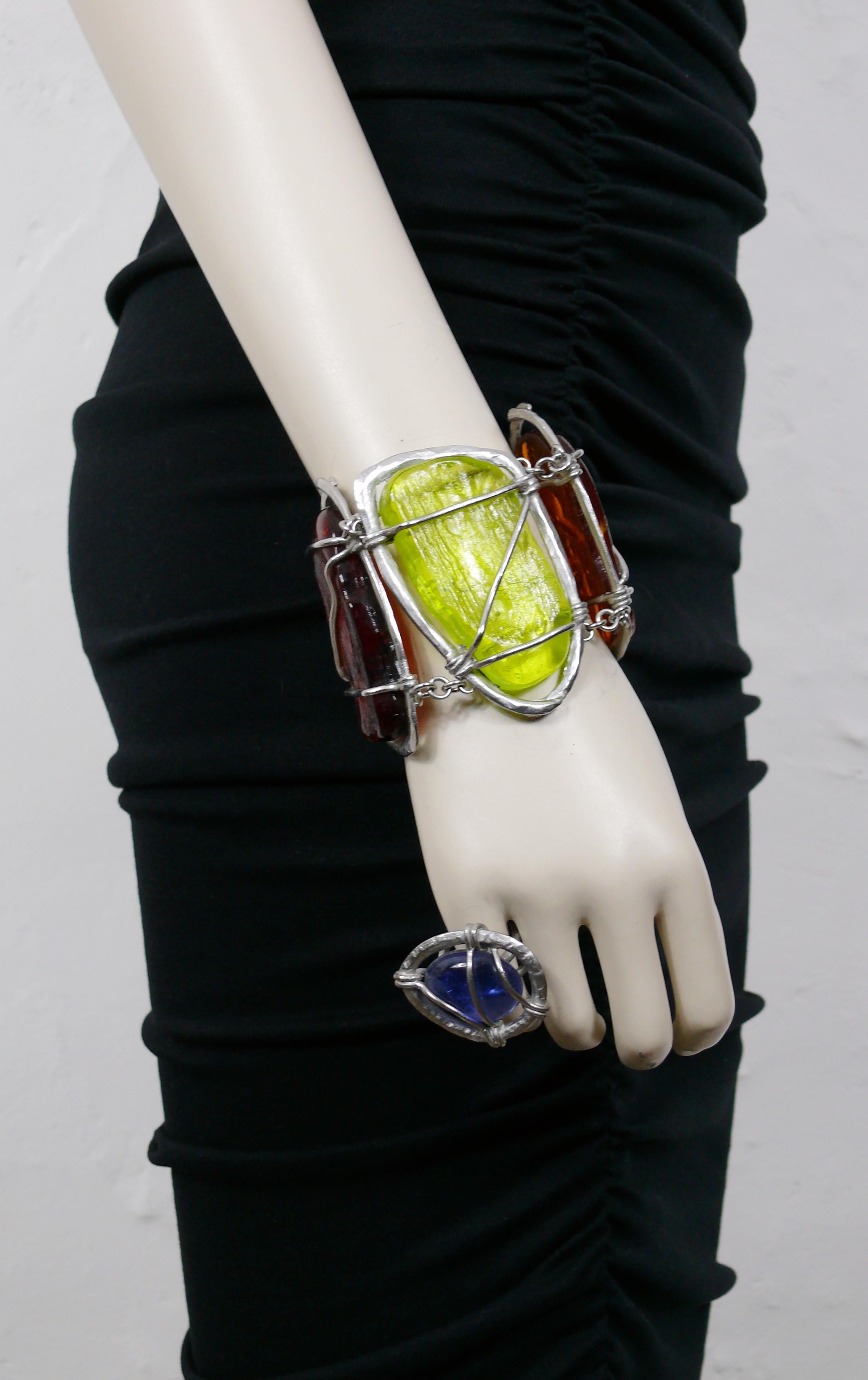 L'ensemble bracelet et bague abrutalistes JEAN PAUL GAULTIER est orné de cabochons de verre multicolores encastrés.

Matériel métallique de couleur argentée.
Patine antique.

Marqué JEAN PAUL GAULTIER sur le bracelet.
La bague est NON