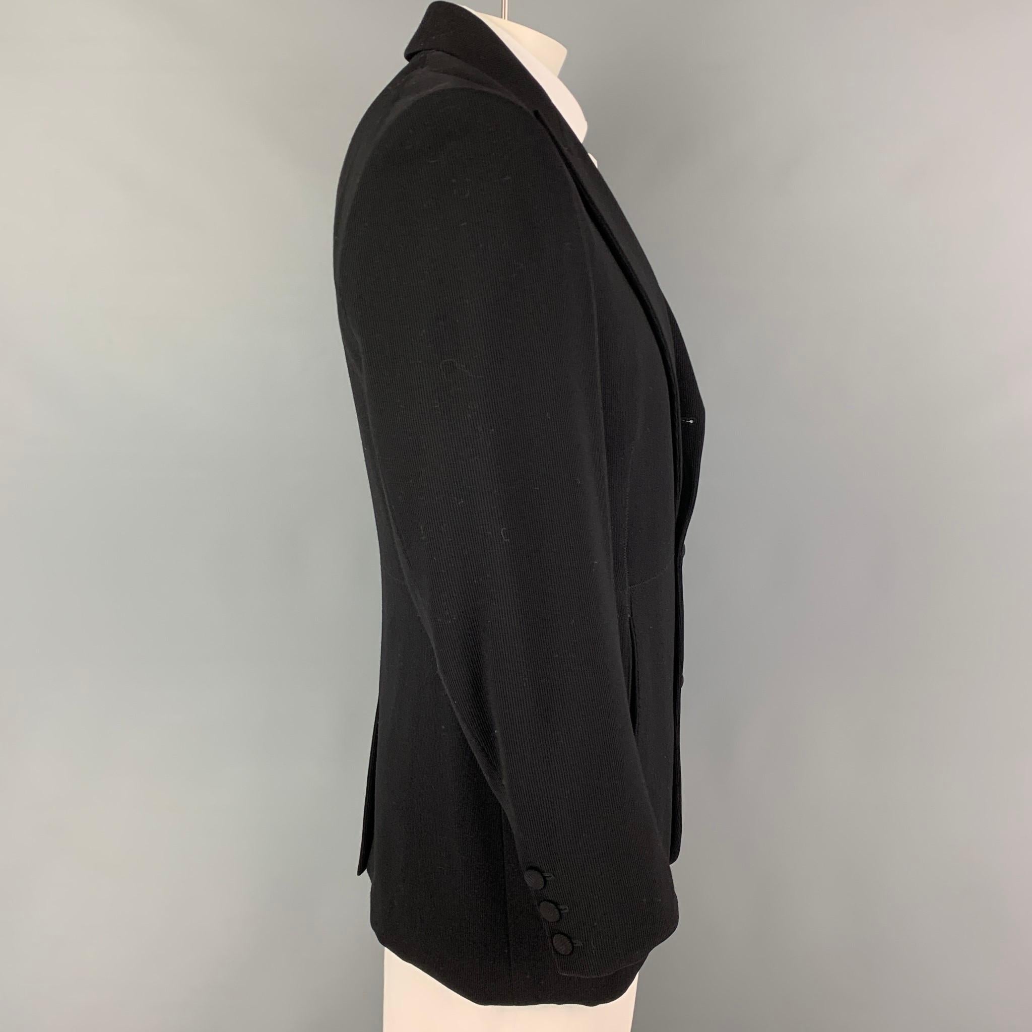 JEAN PAUL GAULTIER HOMME sport coat comes in a black material with a full stripe liner featuring a peak lapel, slit pockets, single back vent, and a three button closure. Made in Italy. 

Very Good Pre-Owned Condition. Light wear at interior.