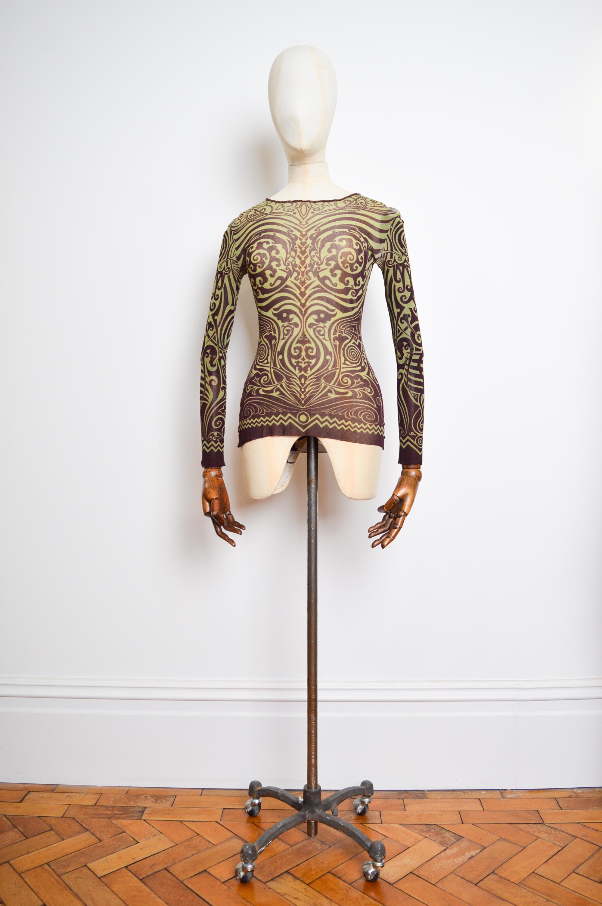 Spring / Summer 1996 Jean Paul Gaultier 'Tribal Tattoo' mesh long sleeve Top. (as seen on the runway modelled by Linda Evangelista)

MADE IN ITALY.  

Measurement are provided in Inches ;
(Stretchy - Laid flat vs Stretched)
Pit to pit - 15.5
