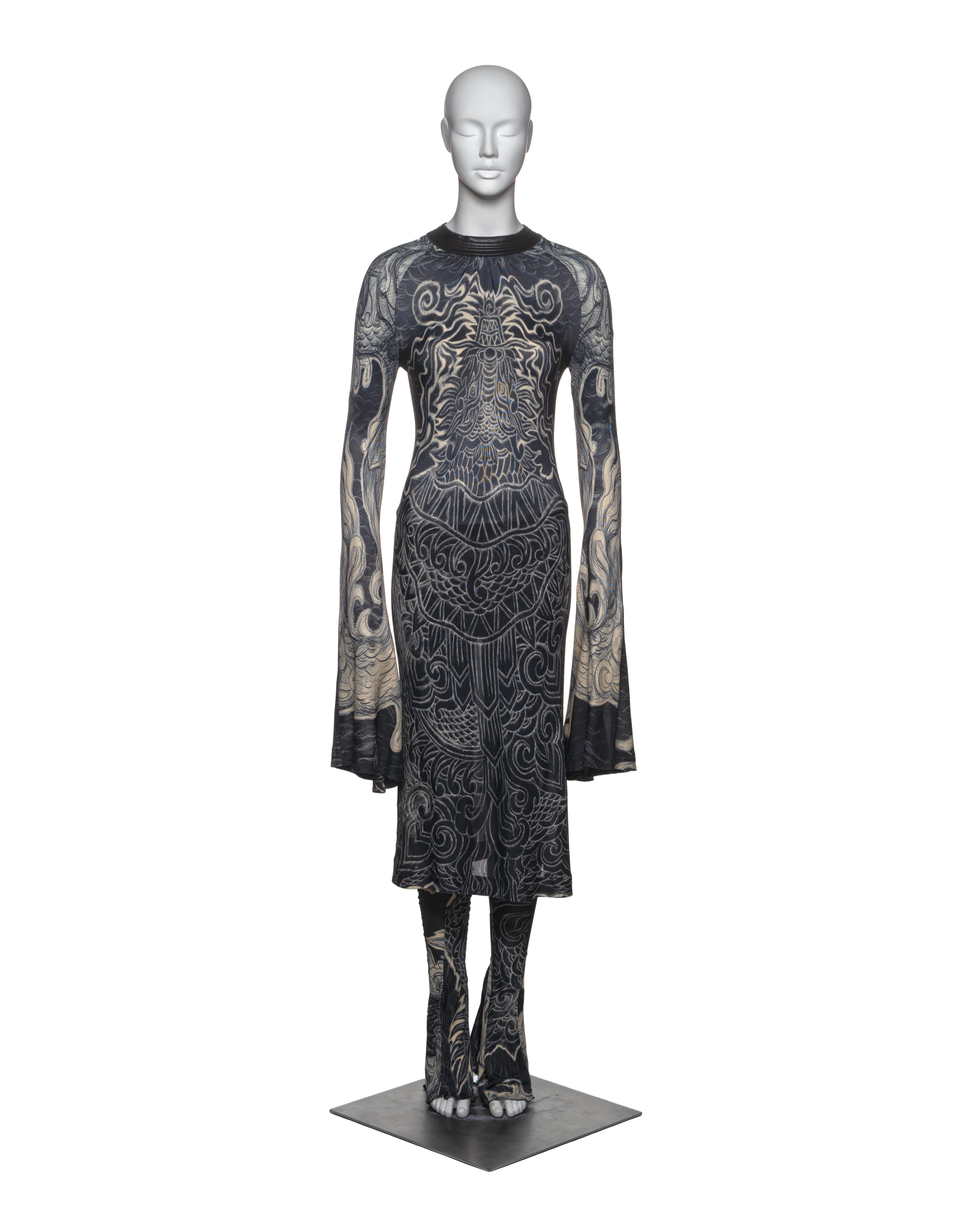 This Jean Paul Gaultier ensemble features a form-fitting, long-sleeve dress with matching pants. Both pieces are crafted from a printed rayon fabric with intricate, tattoo-inspired motifs in a monochrome palette. The print incorporates dragon,