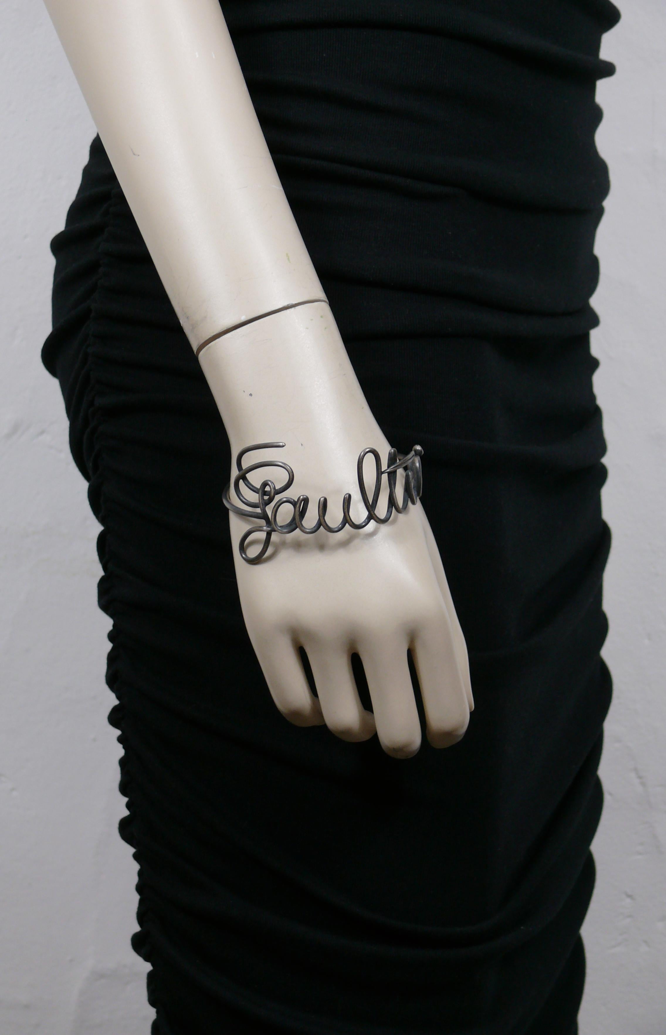 JEAN PAUL GAULTIER vintage gun metal tone bangle bracelet featuring GAULTIER cursive signature.

Slips on (no clasp closure).

Unmarked.

Indicative measurements : circumference approx. 20.73 cm (8.16 inches) / max. width approx. 4 cm (1.57