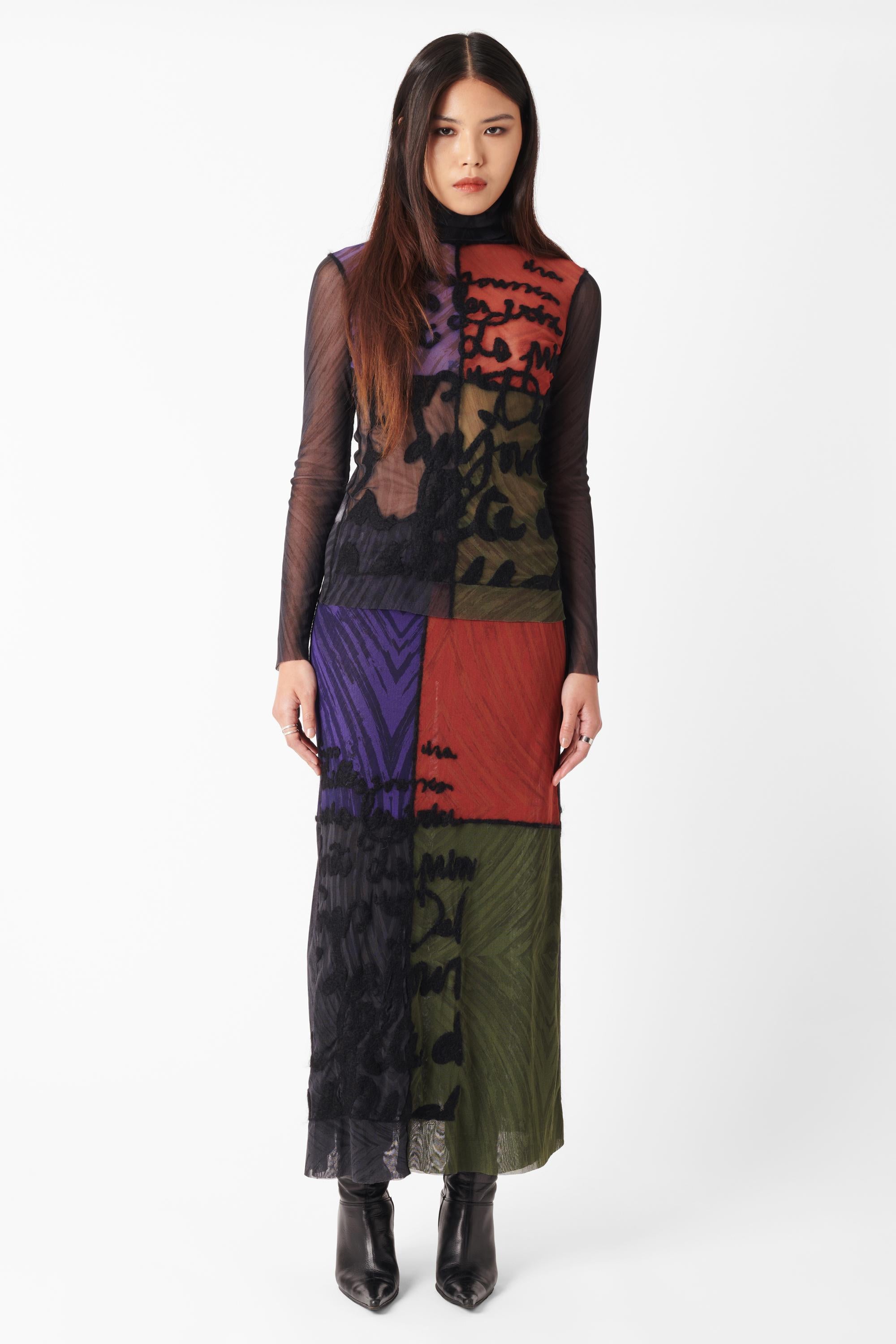 Coordinado de malla bordada Jean Paul Gaultier Otoño Invierno 2001. Presenta cuello alto, paneles de bloques de color morado, verde, negro y rojo, adornos de mohair, palabras bordadas en 3D y doble capa de malla en la falda. Hay que tener en cuenta