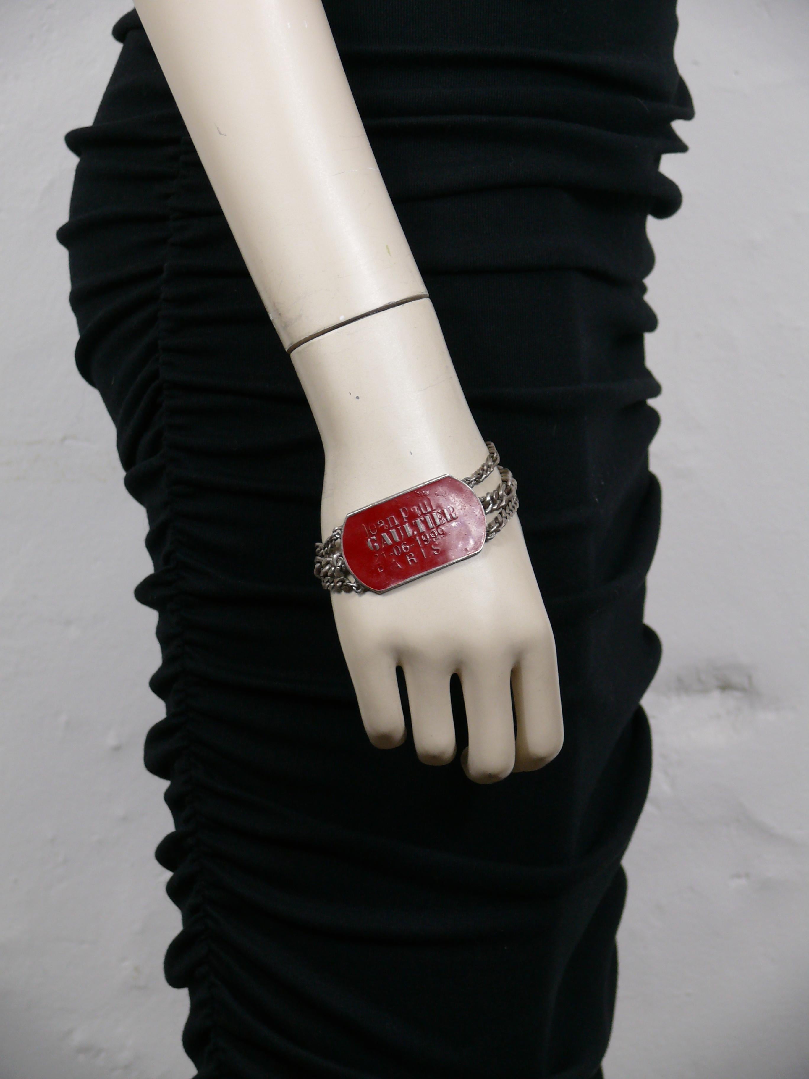 JEAN PAUL GAULTIER Vintage-Armband aus silberfarbenem Metall mit mehreren Ketten und einem militärisch inspirierten ID-Tag mit roter Emaille und der Prägung JEAN PAUL GAULTIER 21-06-1999 PARIS.

Faltbarer Verschluss.

Unmarkiert.

Ungefähre Maße: