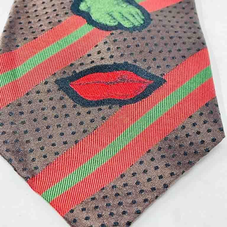 Diese gestreifte Krawatte ist sehr Gaultier mit einzigartigen Designs auf einer klassischen Streifenkrawatte! Rote Lippen. Auge Grüner Fuß. Blaue Hand.

Ultra Selten. Sammlerstück.
Länge - 56 Zoll
Breite - 3 1/2 Zoll.
Seide
Hergestellt in Italien
