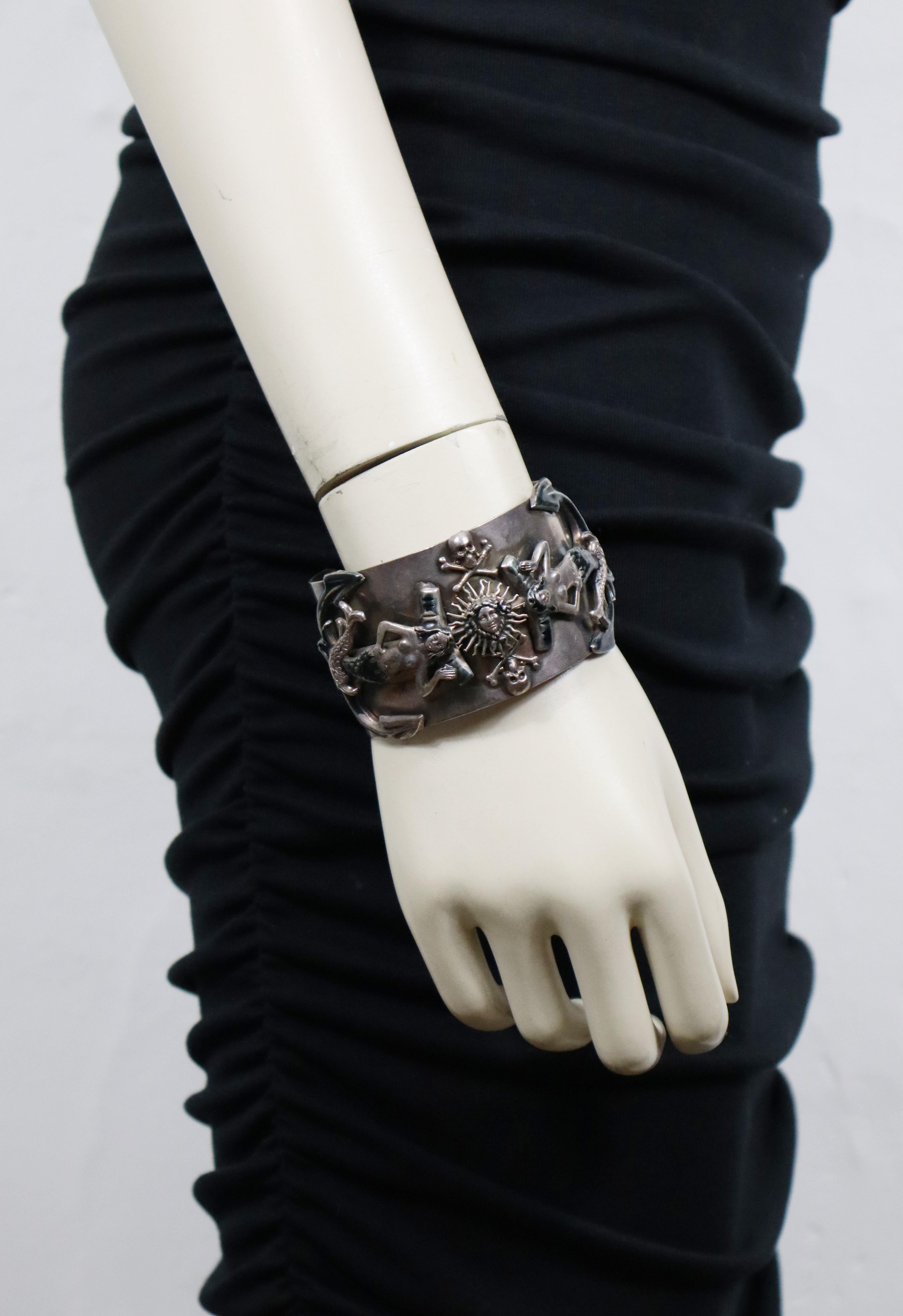 JEAN PAUL GAULTIER vintage dark oxidized silver tone metal cuff bracelet featuring mermaids and anchors embellished with blue enamel, dolphins, memento mori and radiant sun face.

The dark oxidized patina is from original manufacturing.

Marked