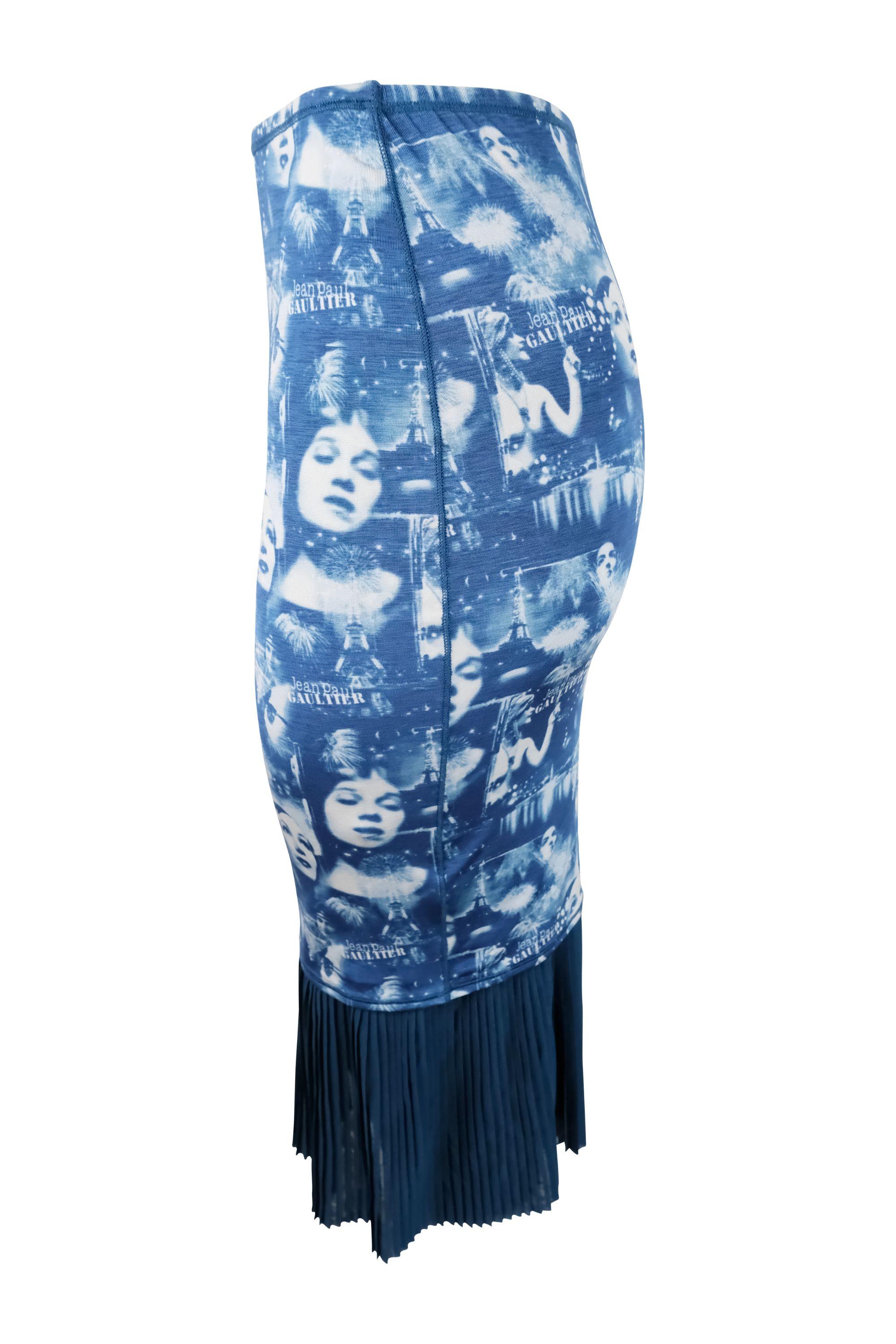 This Jean Paul Gaultier skirt has a distinctive print in shades of blue featuring various faces and iconic Parisian imagery, including the Eiffel Tower, with the brand’s logo scattered throughout the pattern. The material is stretchy, creating a