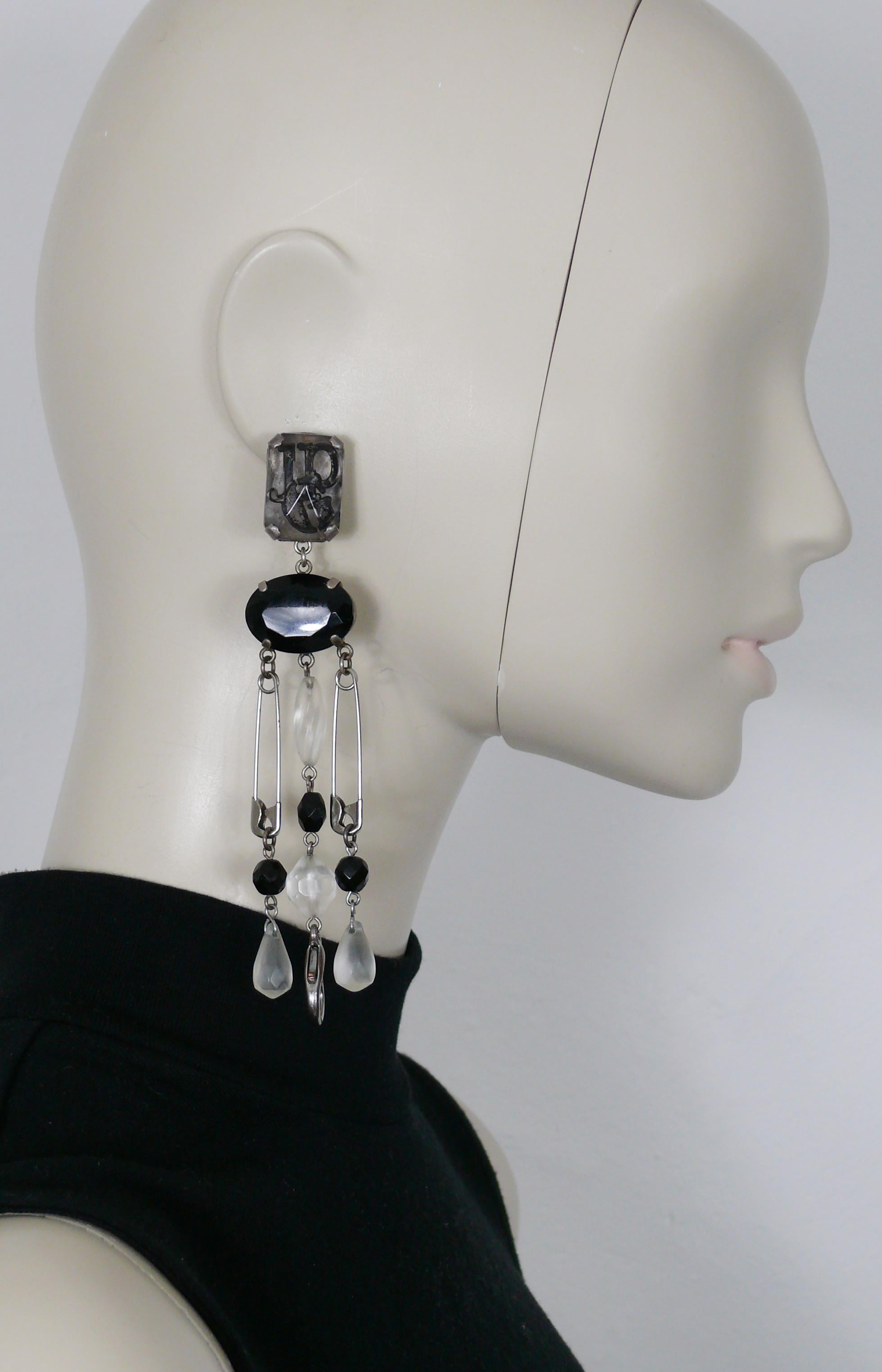 JEAN PAUL GAULTIER vintage punk safety pin shoulder duster dangling earrings (clip-on) featuring JPG logo inlaid resin top, black resin cabochon, black and clear acrylic beads and a large lobster clasp closure.

Silver tone metal hardware.
Antiqued