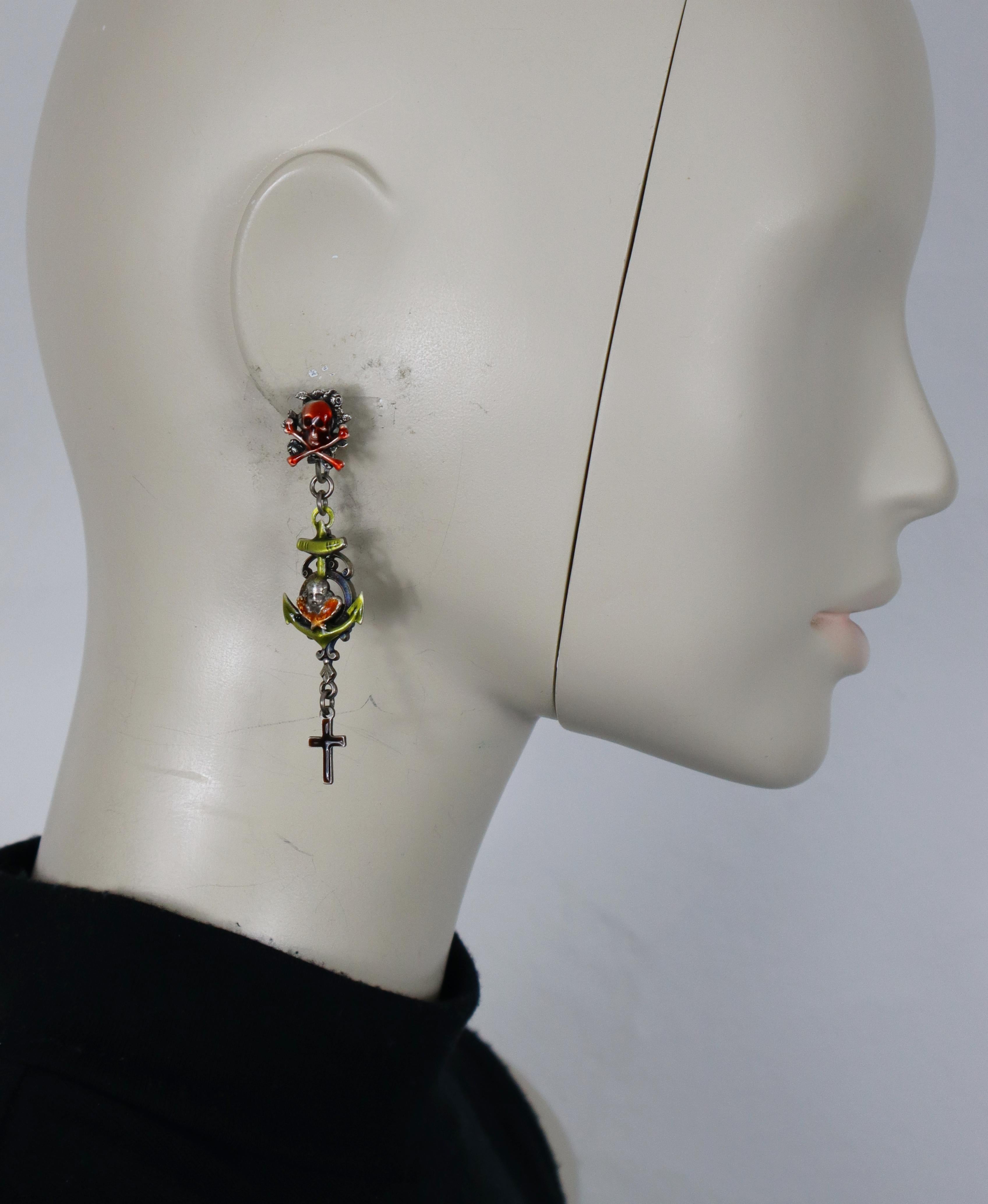 JEAN PAUL GAULTIER vintage clip-on dangle earrings in antiqued silver-tone metal, showcasing a striking raised skull and crossed bones, a cherub motif with anchor, and a cross charm all enhanced with vibrant multicolored enamel.

Marked