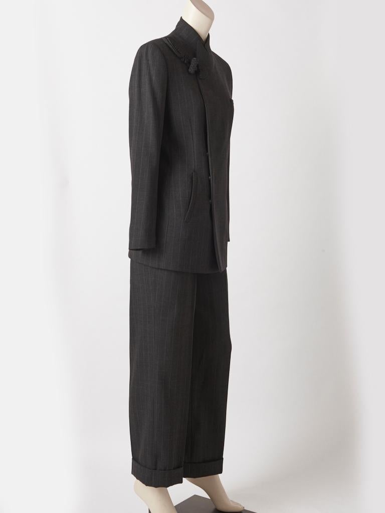 Jean Paul Gaultier, charcoal grey, wool crepe, chalk stripe pantsuit, having a long fitted jacket with a convertible collar that is mandarin style when closed.  There is a an exaggerated frog closure at the shoulder. When the  closure is open it has