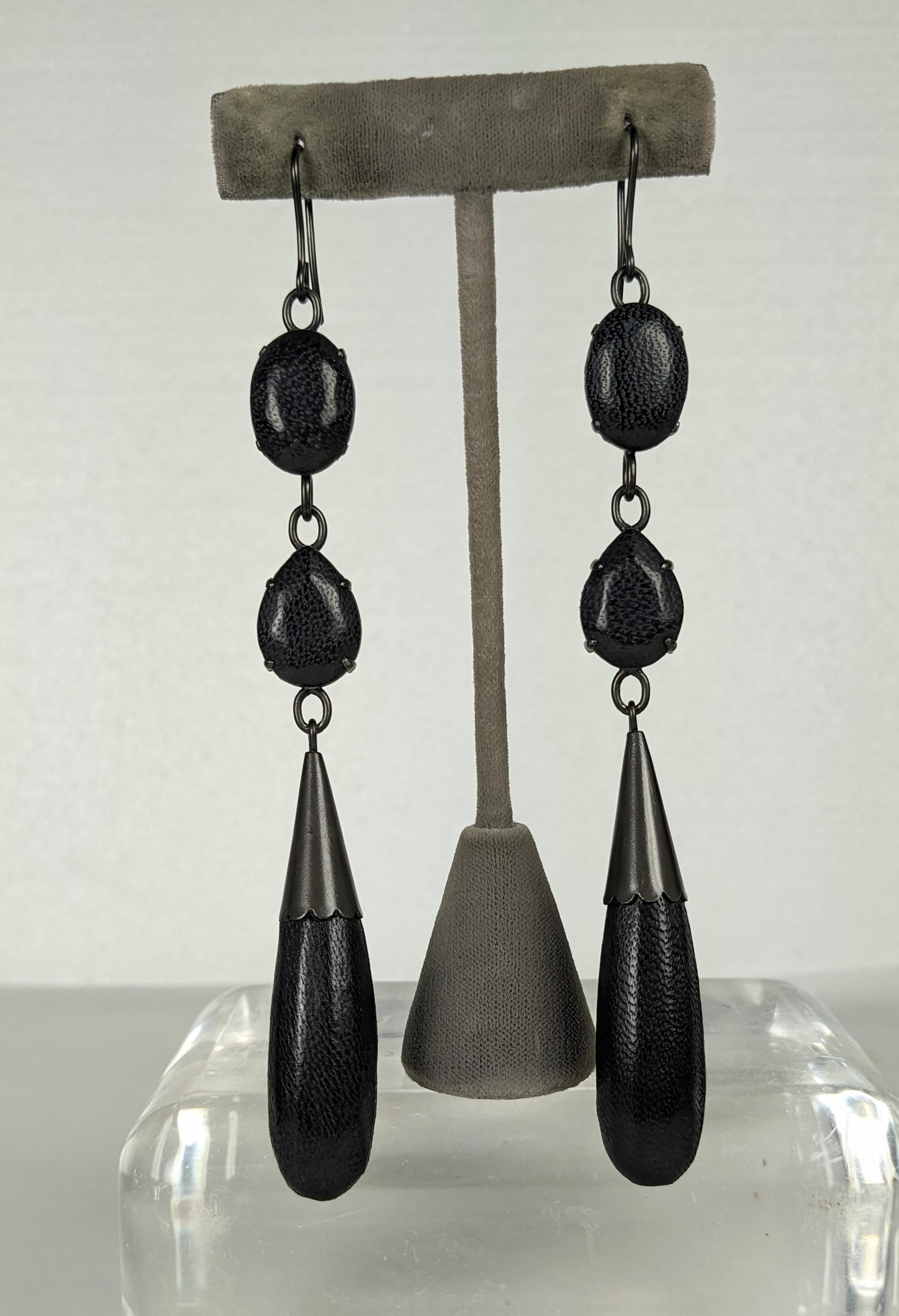 Insoliti orecchini lunghi in pelle Jean Paul Gaultier. Composto da cabochon ovali, goccioline sfaccettate e lunghi pendenti a goccia, il tutto rivestito in pelle d'agnello nera. Il tutto incastonato in metallo bronzo annerito. Firmato Jean Paul