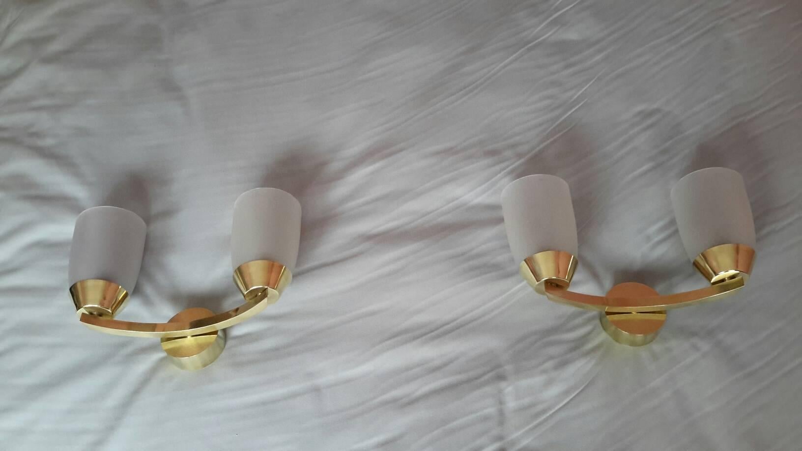 Elegant pair of Modernist double sconces from the mid-1950s in brass with original frosted glass shades in the style of Jean Perzel.
The sconces are in excellent condition, rewired and comply with the US Standard (bayonet bulb, 60 watts maxi per