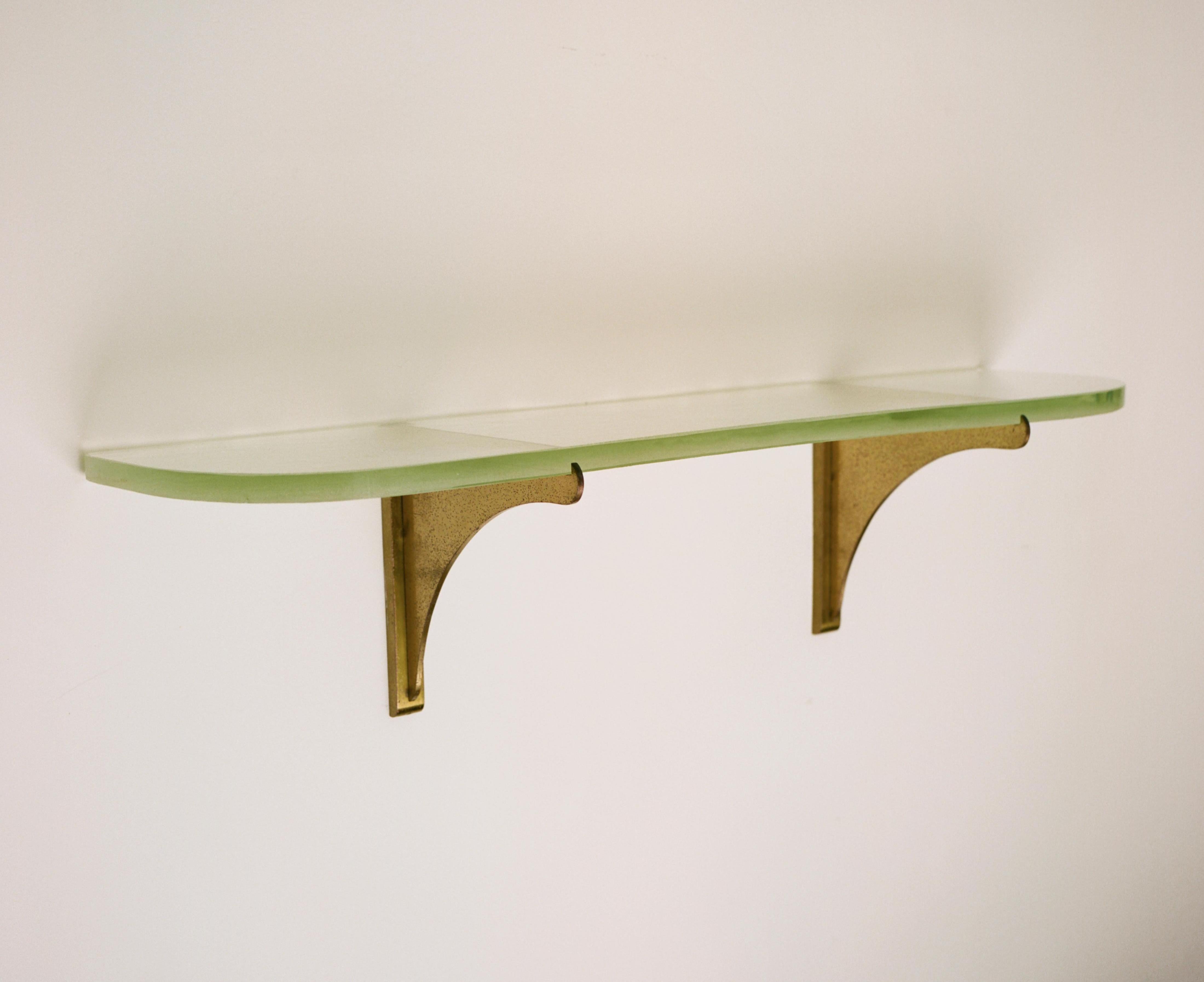 A wall shelf made up of two brushed brass brackets and a curved, heavy piece of sandblasted glass produced by Saint Gobain in France. Jean Perzel was a German-born French glassmaker, goldsmith, and designer who was a key figure in the early 20th