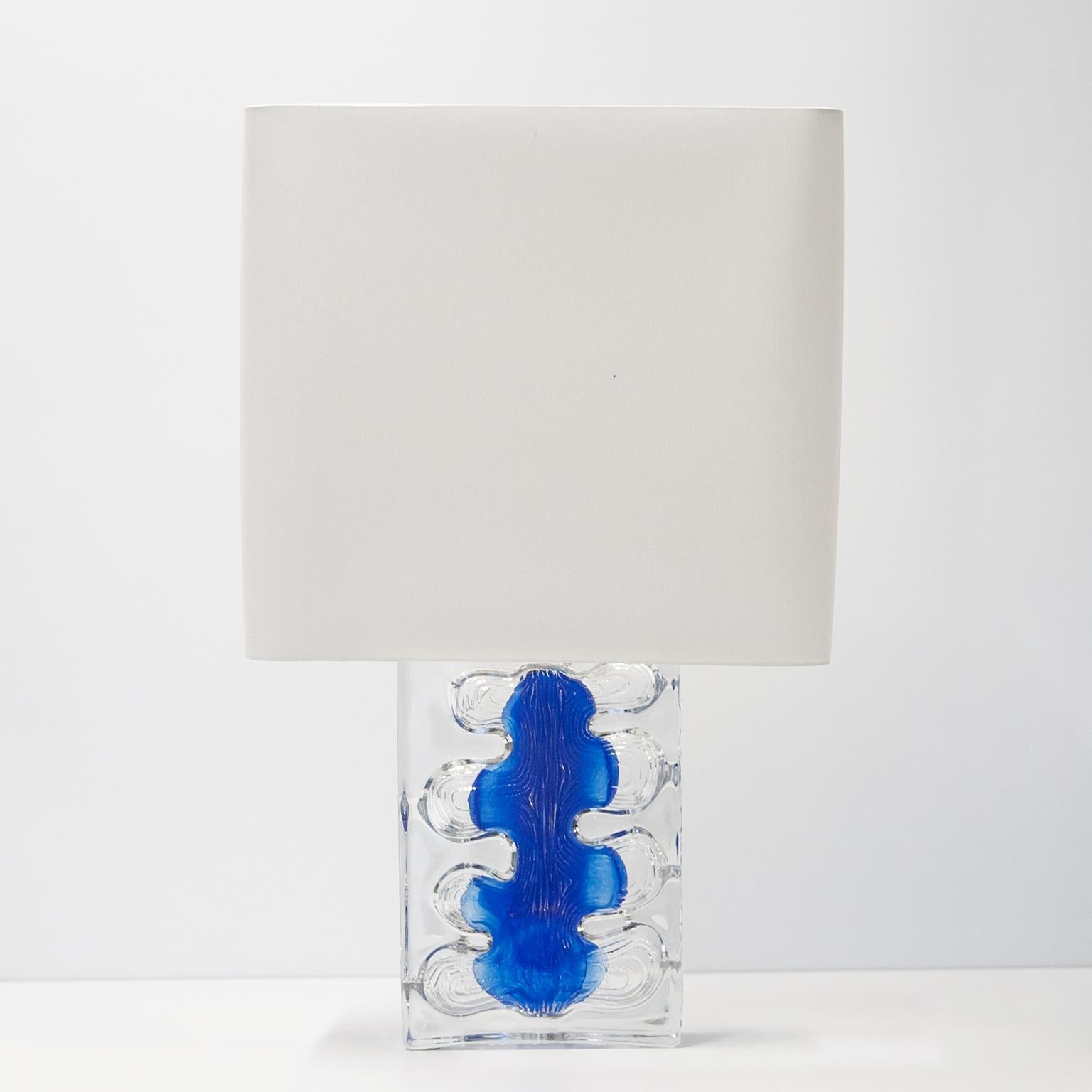 Elegante lámpara de sobremesa diseñada en vidrio artístico transparente y azul con pantalla blanca. Atribuido a Jean-Pierre Demarchi y producido por Daum Nancy en Francia en la década de 1970. Grabado en el cristal por Daum Nancy. Excelente estado