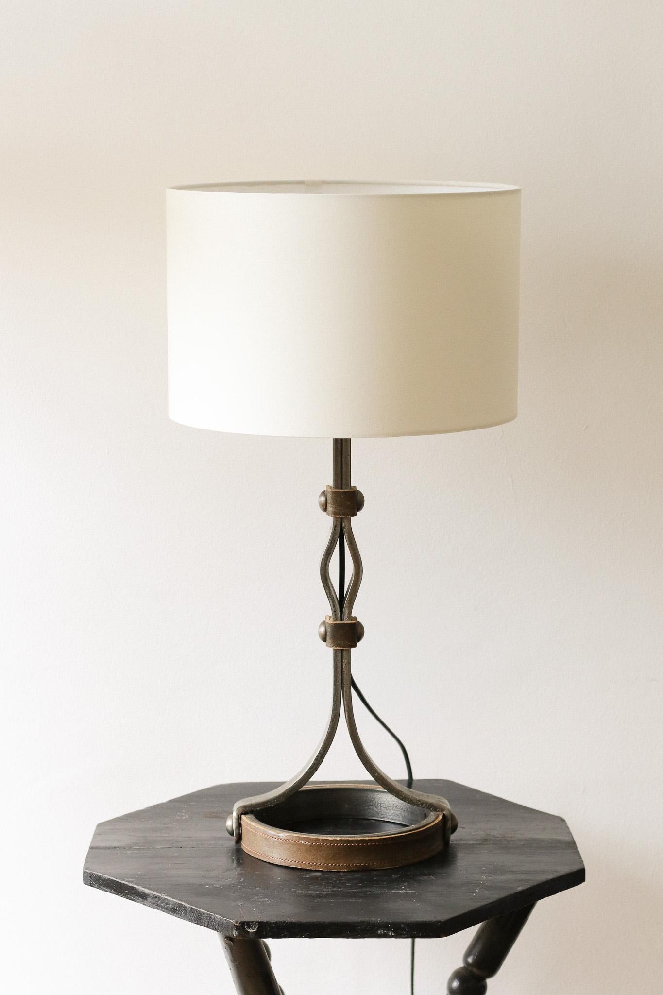 A wrought iron and studded brown leather table lamp by Jean-Pierre Ryckaert. Heavy and skilfully made with large rivets and circular base.

France, Circa 1950.

Height (with shade): 60cm
Height (without shade, to top of bulb holder): 45cm
Width