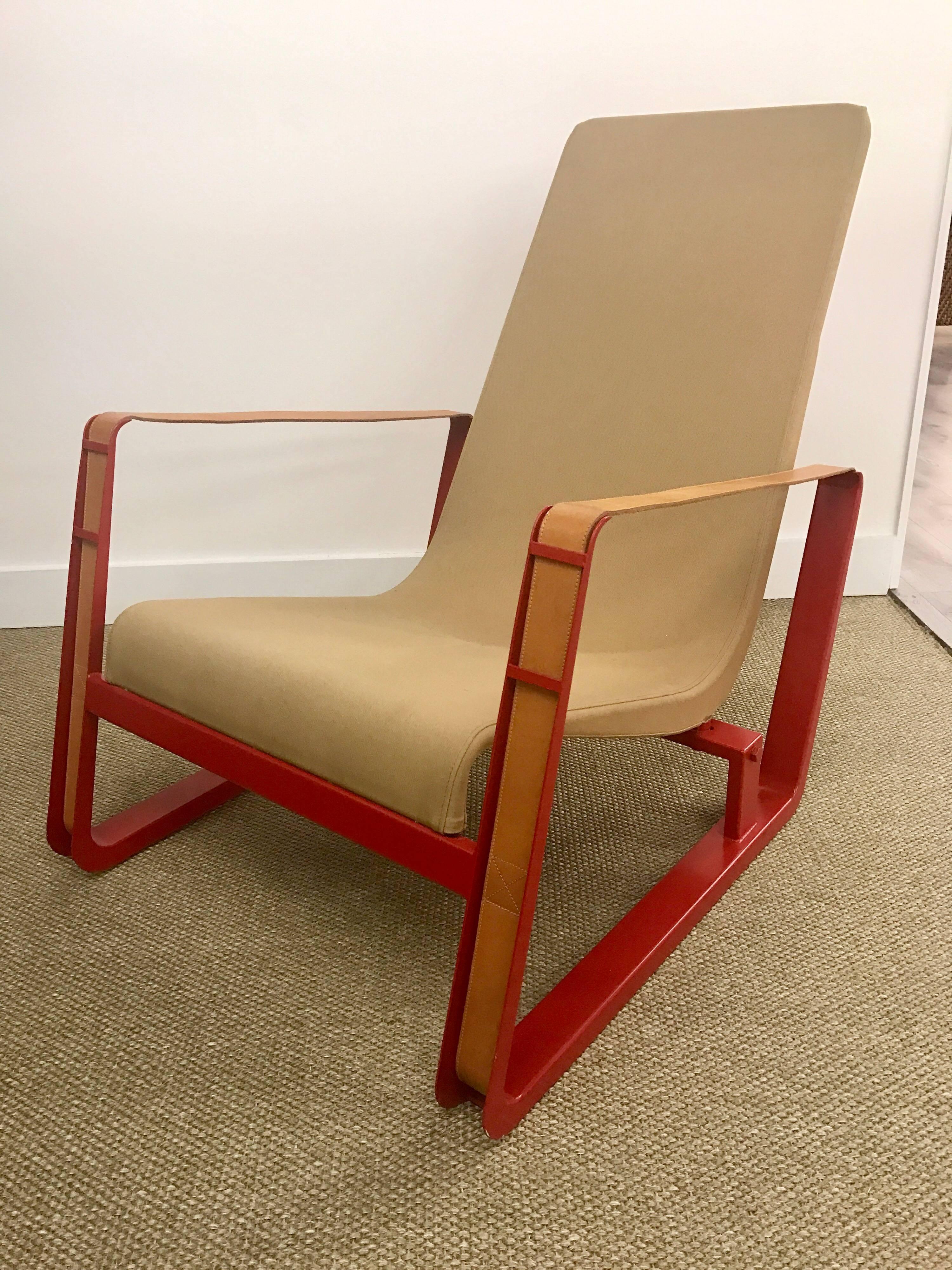 This pair of Jean Prouve Cite lounge chairs for Vitra are low and comfortable chairs and upholstered in canvas with a molded sheet steel, powder-coated in Japanese red. Amazingly beautiful and sexy leather arm straps that attach in back by a buckle.